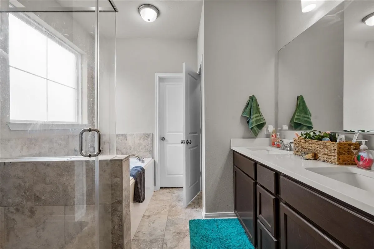 Full bathroom with double vanity, a stall shower, a garden tub, and tile patterned flooring