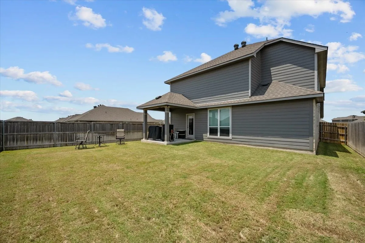 Back of house with roof with shingles, a fenced backyard, and a patio area