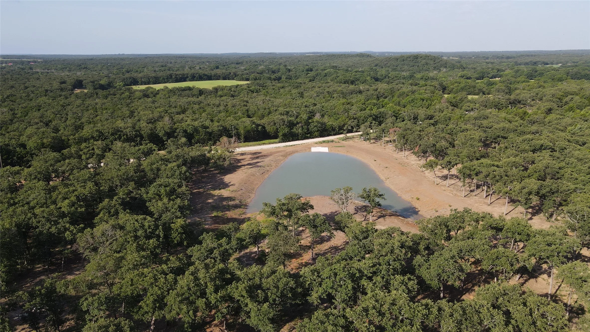 Aerial view of property's location featuring a heavily wooded area and a large body of water