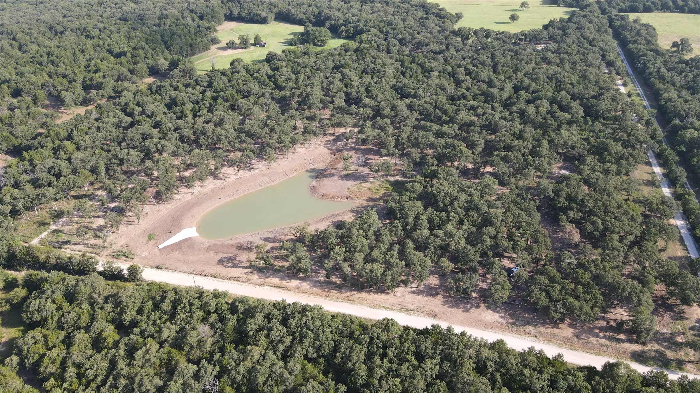 Aerial view of property and surrounding area with a forest and a large body of water