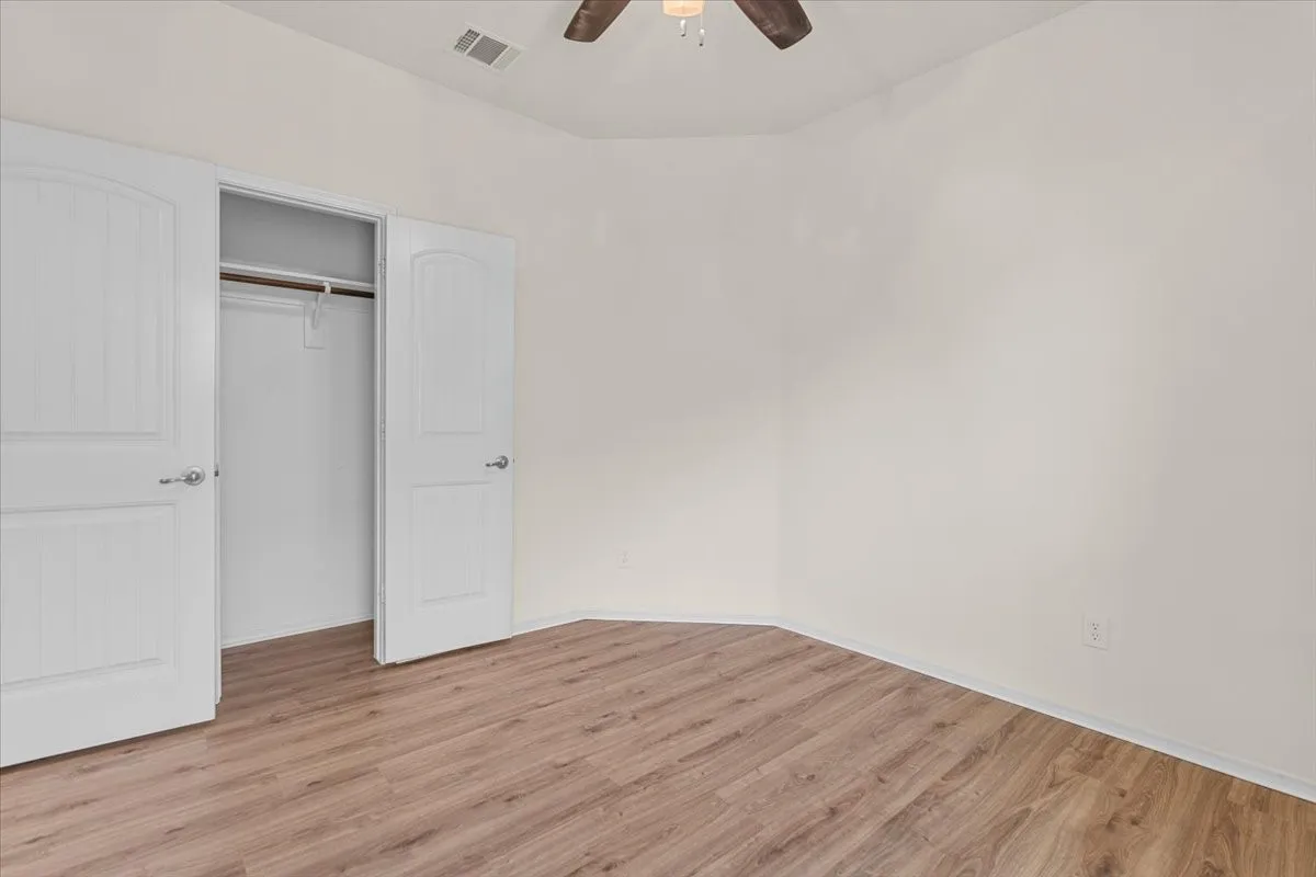Unfurnished bedroom with light wood finished floors, ceiling fan, and a closet