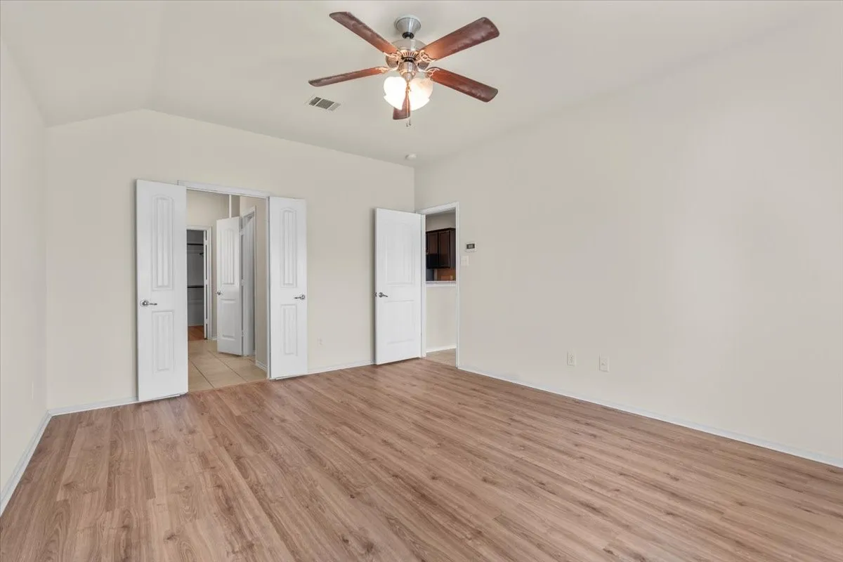 Unfurnished bedroom with light wood finished floors, lofted ceiling, and a ceiling fan