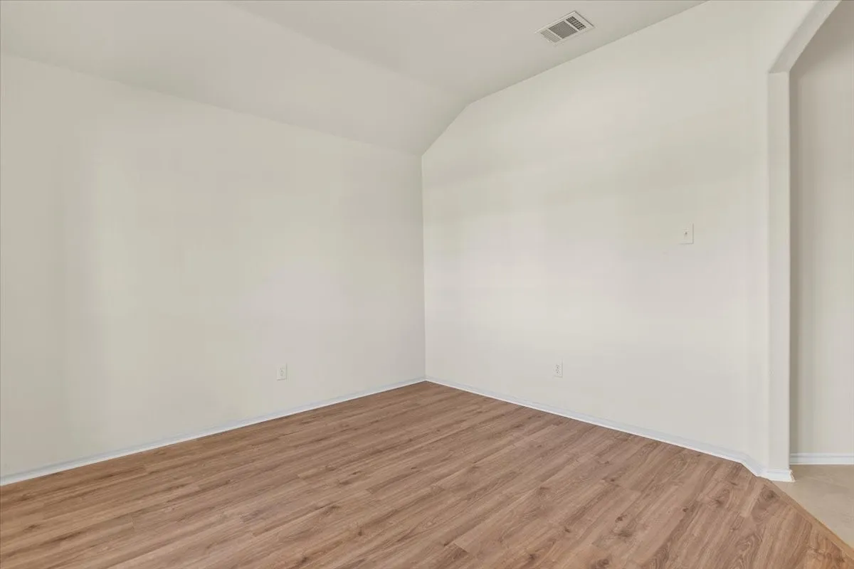 Unfurnished room featuring light wood-type flooring and vaulted ceiling