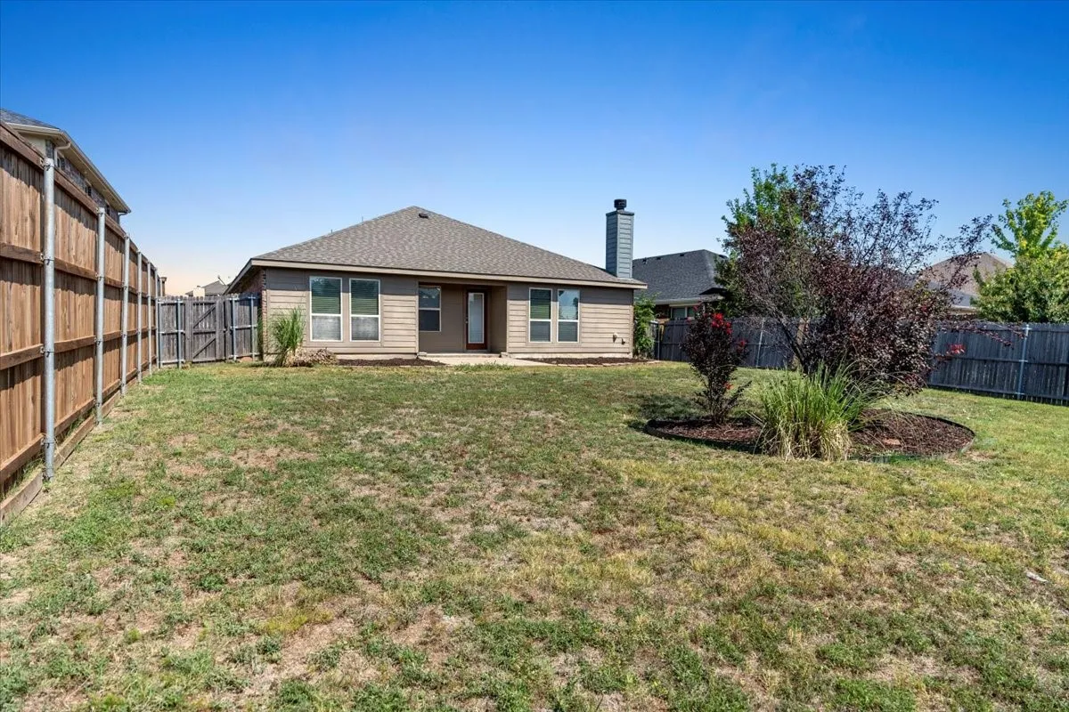 Back of property featuring a fenced backyard, a patio area, roof with shingles, and a chimney