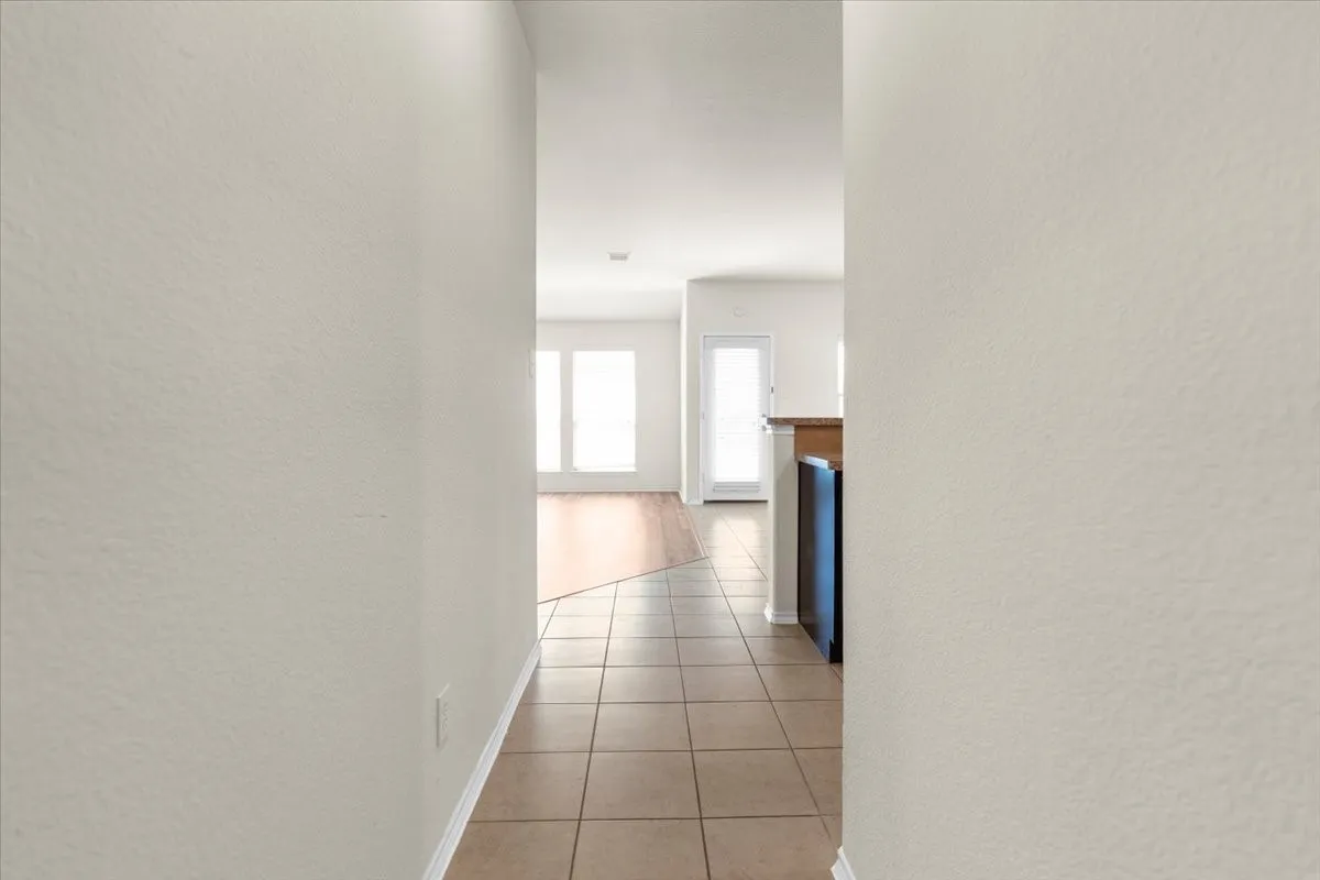 Corridor with a textured wall and light tile patterned floors