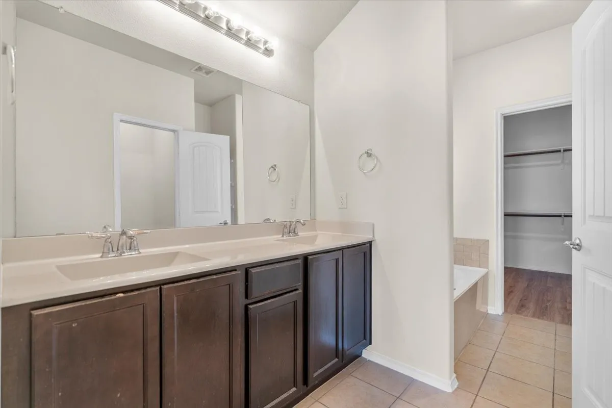 Full bathroom with tile patterned flooring, double vanity, and a bath
