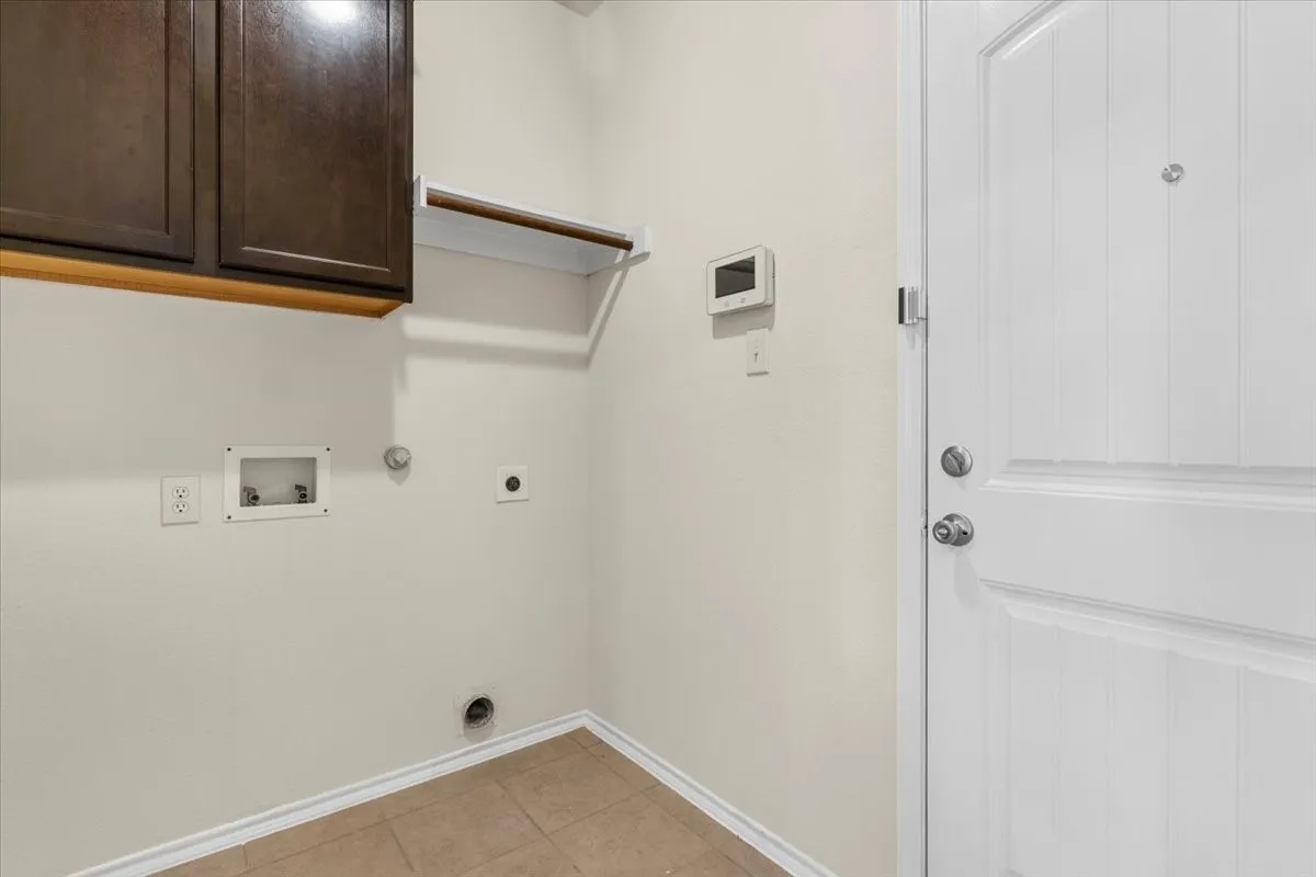 Washroom featuring electric dryer hookup, cabinet space, hookup for a gas dryer, hookup for a washing machine, and light tile patterned floors