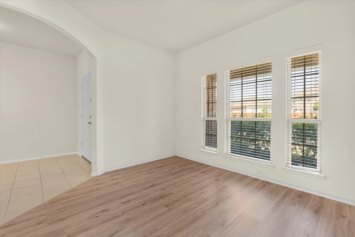 Empty room featuring arched walkways and light wood-style floors