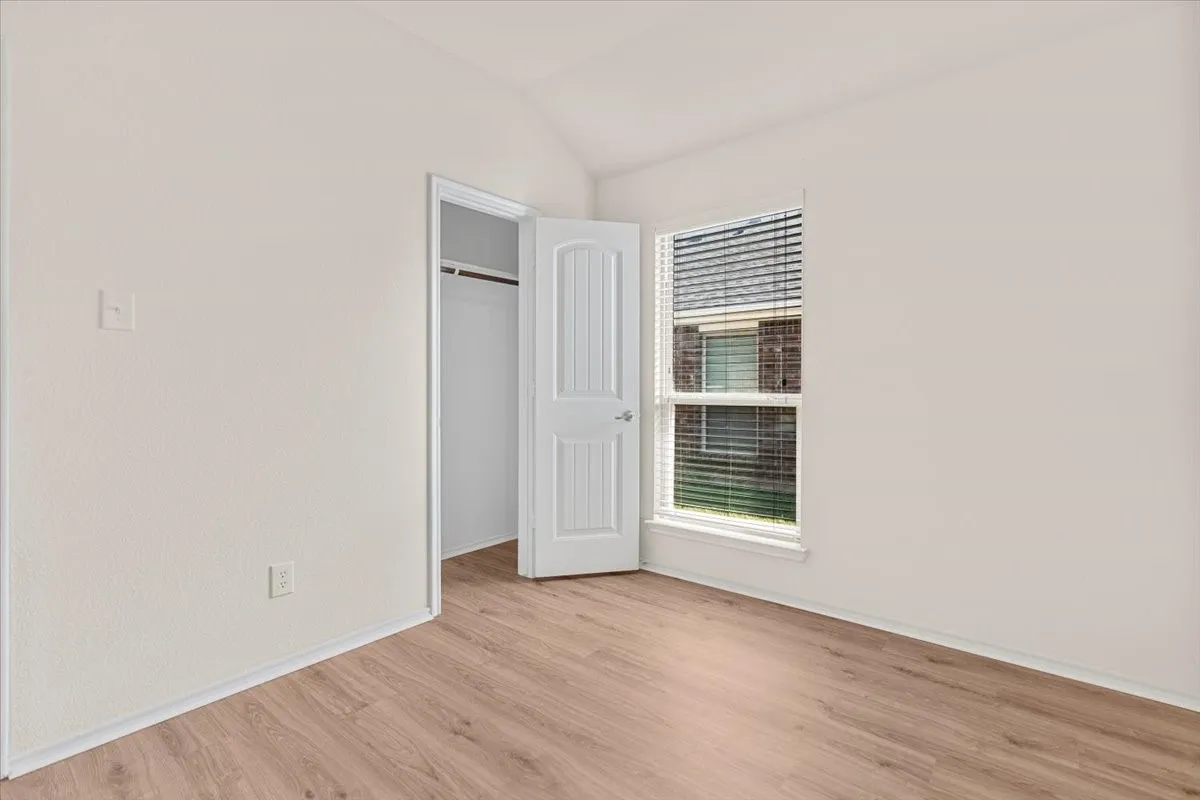 Unfurnished bedroom featuring light wood-style floors, lofted ceiling, and a closet