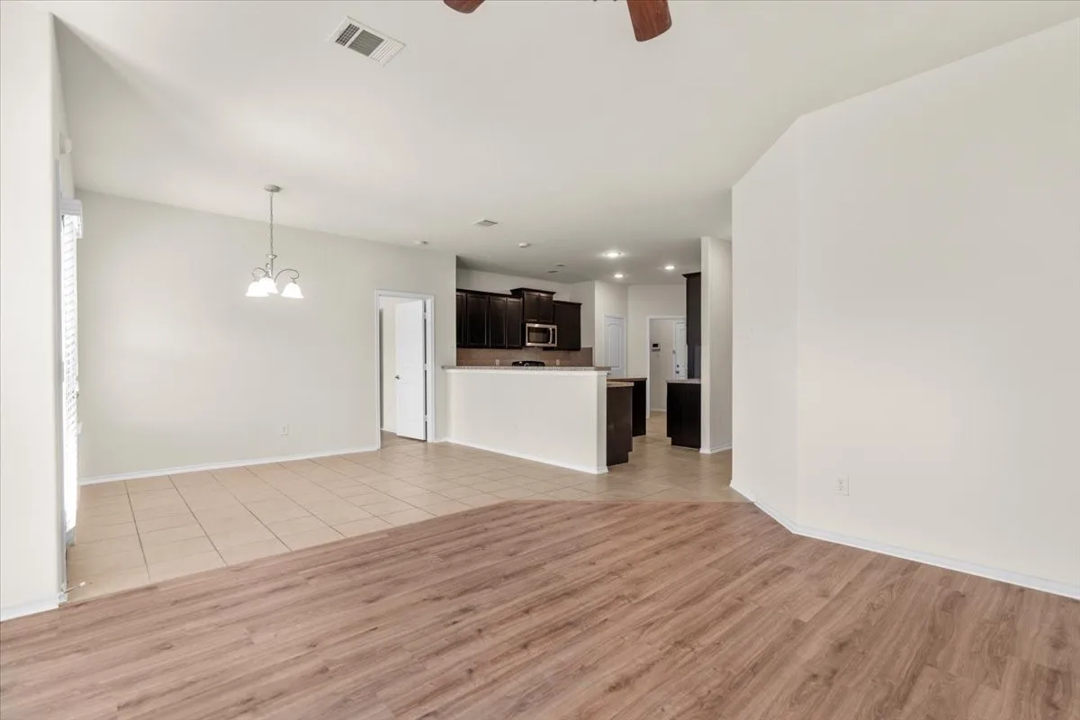 Unfurnished living room with light tile patterned floors, a chandelier, and ceiling fan