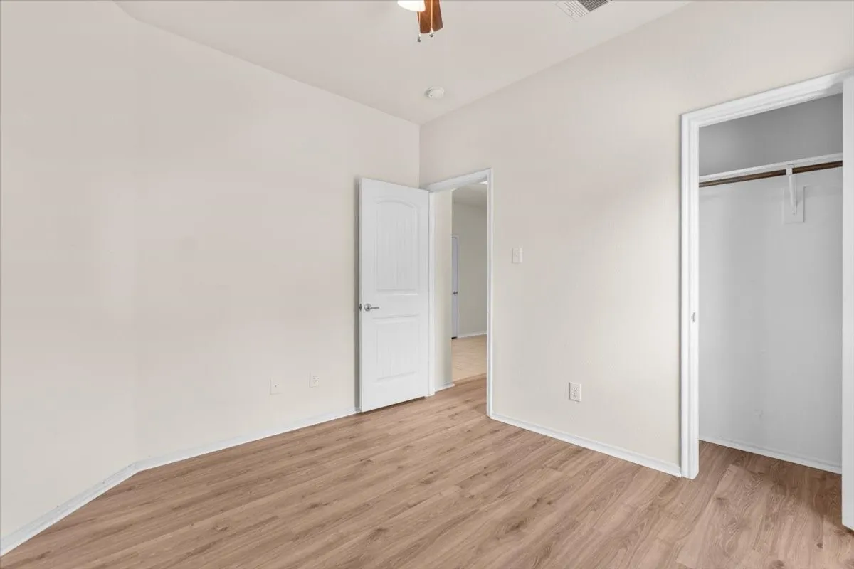 Unfurnished bedroom featuring light wood-style flooring, a closet, and a ceiling fan