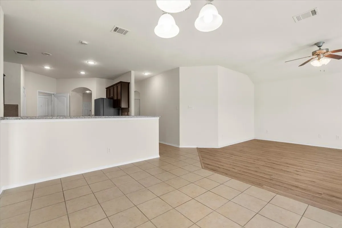 Empty room featuring light tile patterned floors, arched walkways, a ceiling fan, and recessed lighting