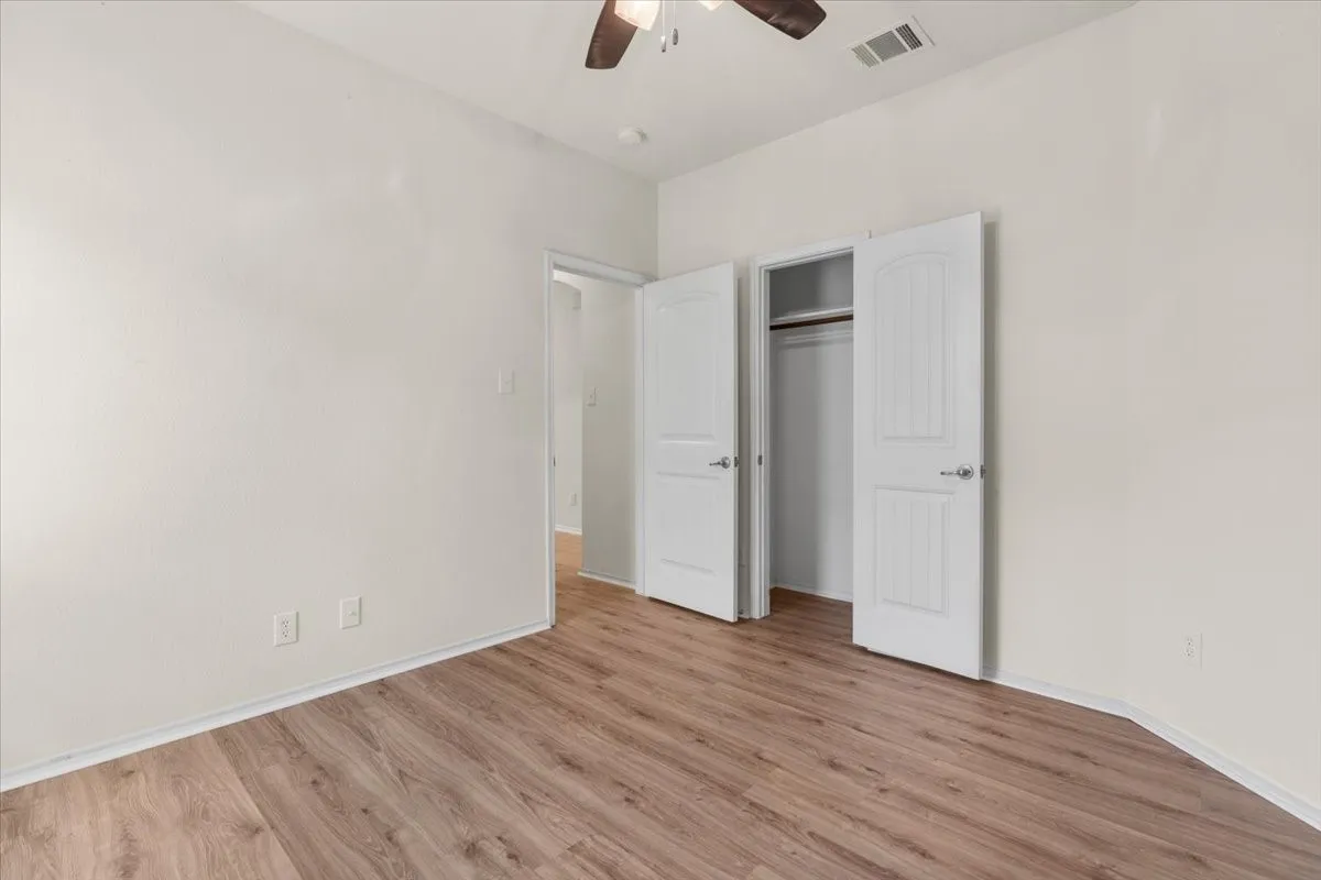 Unfurnished bedroom with wood finished floors, a ceiling fan, and a closet