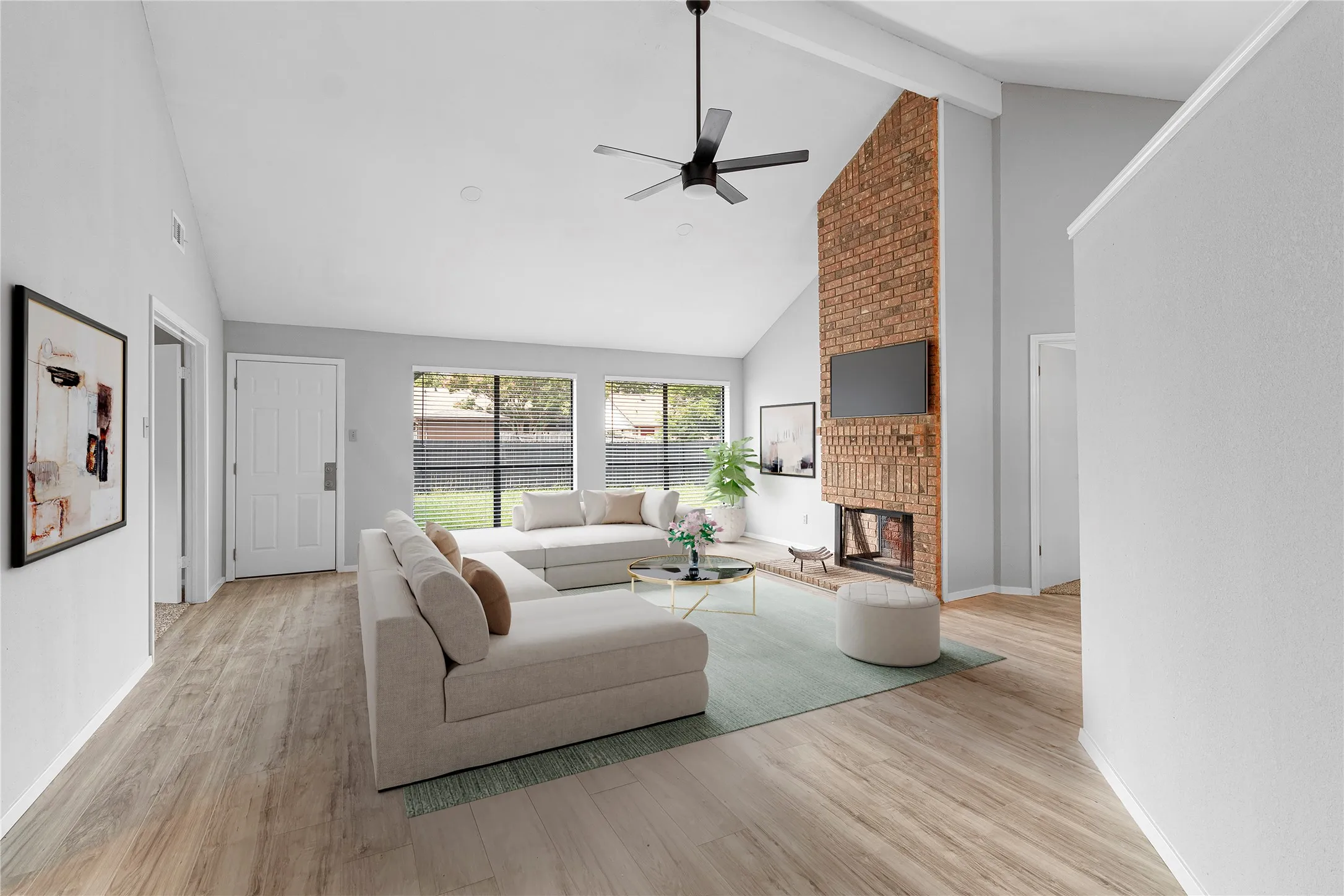 Living area featuring high vaulted ceiling, light wood-style floors, beamed ceiling, a fireplace, and ceiling fan