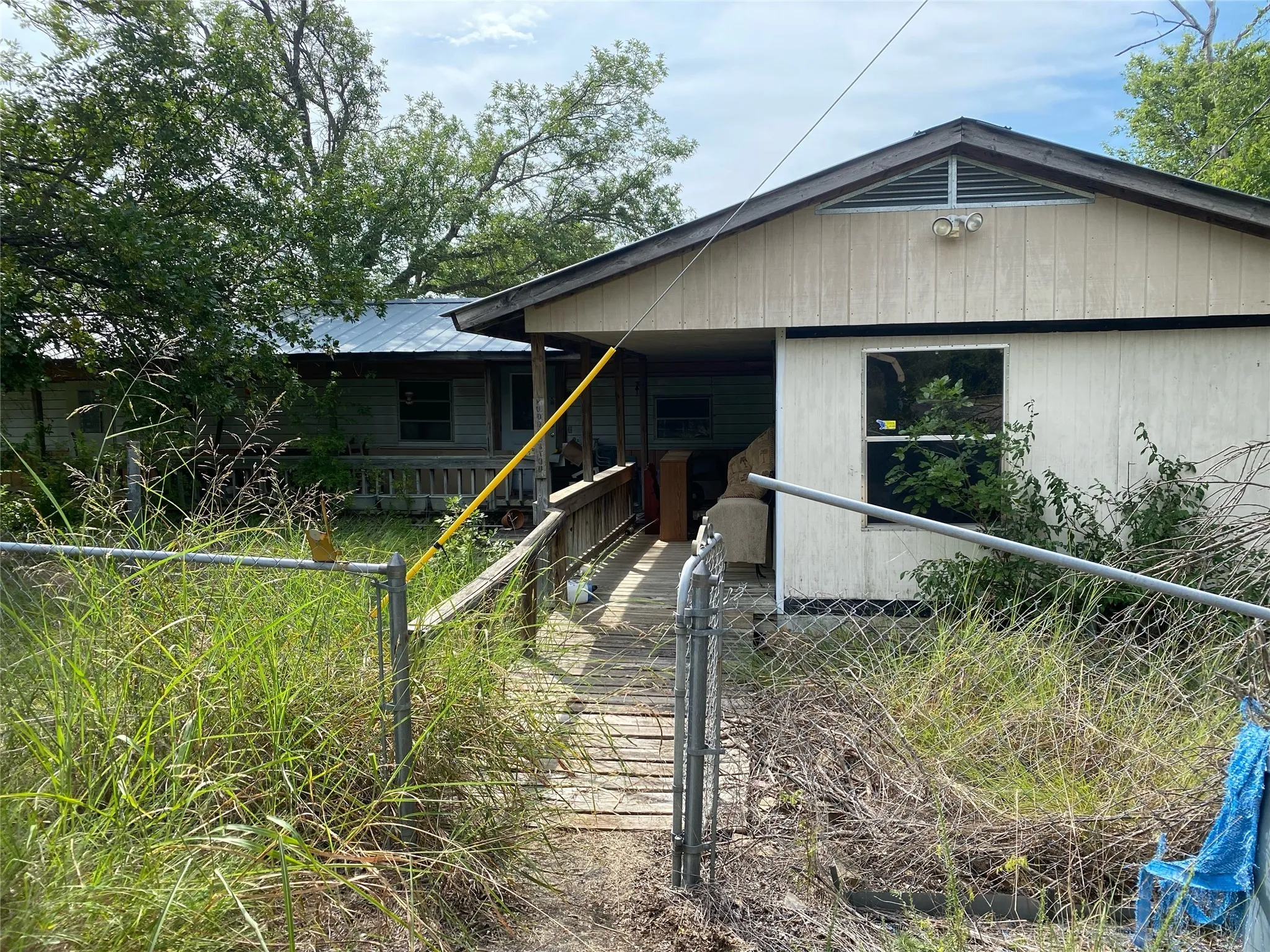 View of front facade with a gate, a fenced front yard, and a metal roof