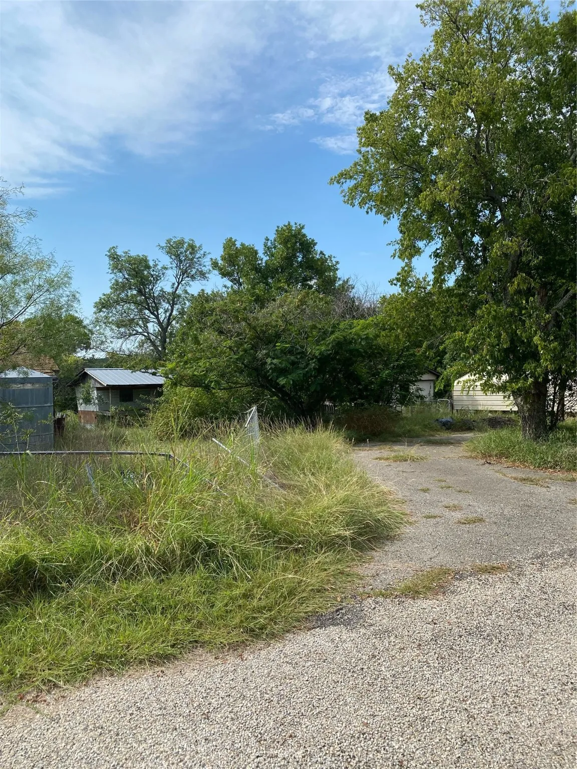 View of dirt / gravel driveway featuring view of scattered trees
