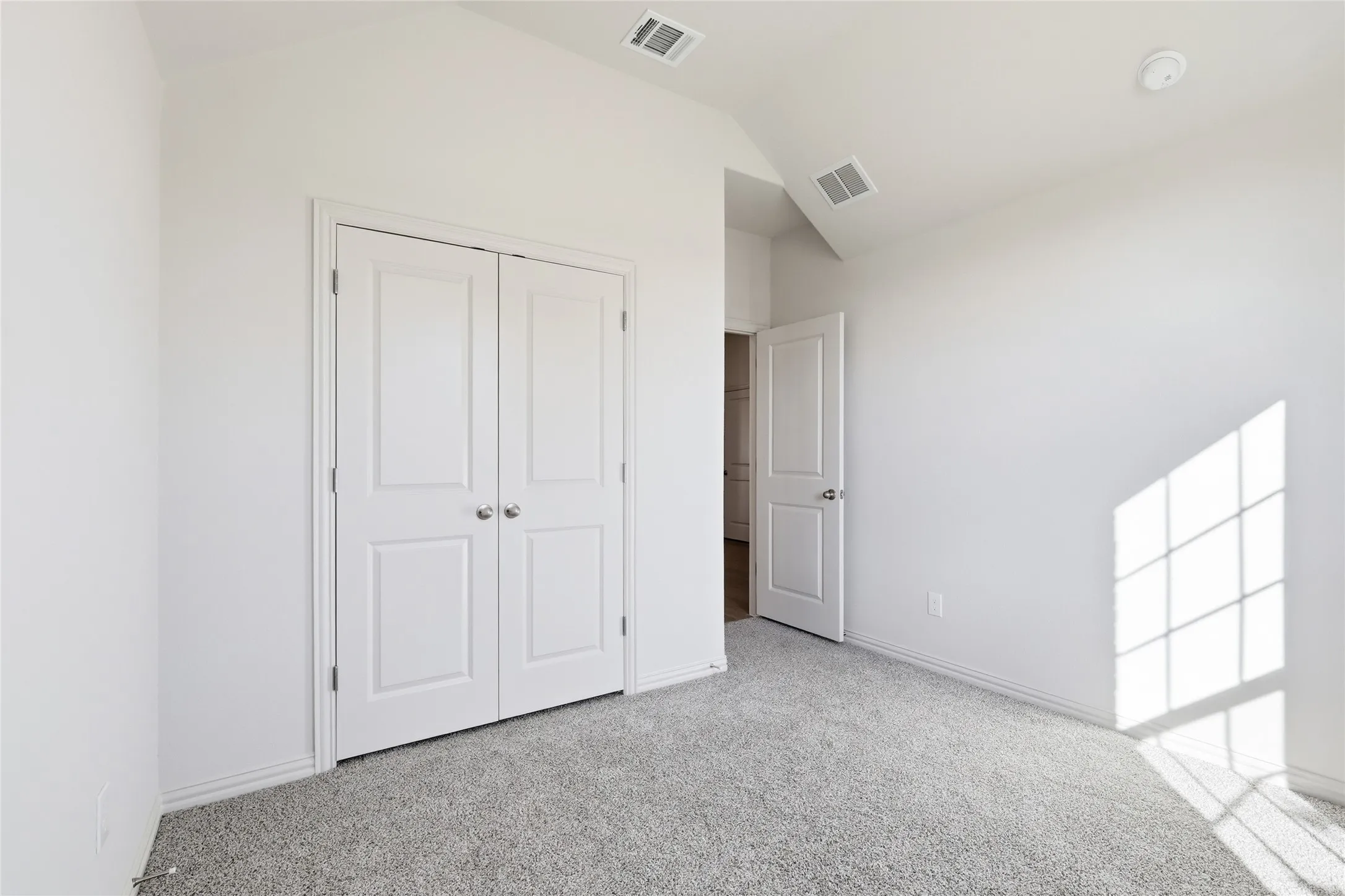 Unfurnished bedroom with lofted ceiling, light colored carpet, and a closet