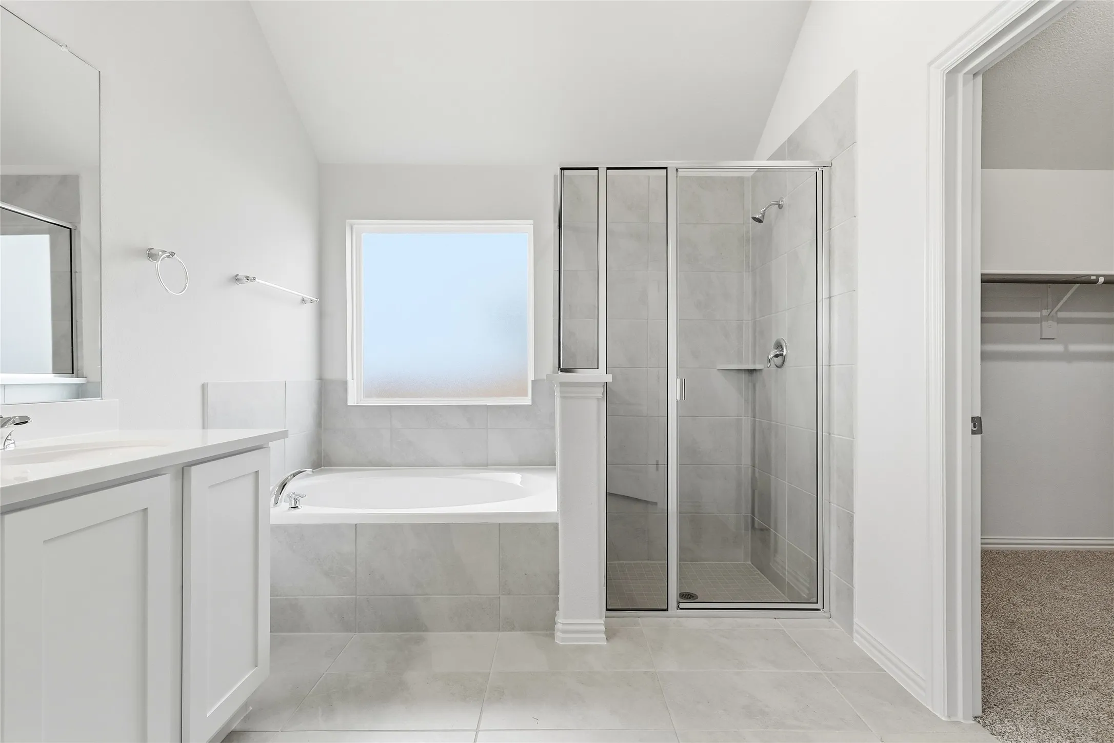 Full bath featuring a bath, vanity, a spacious closet, vaulted ceiling, and a shower stall
