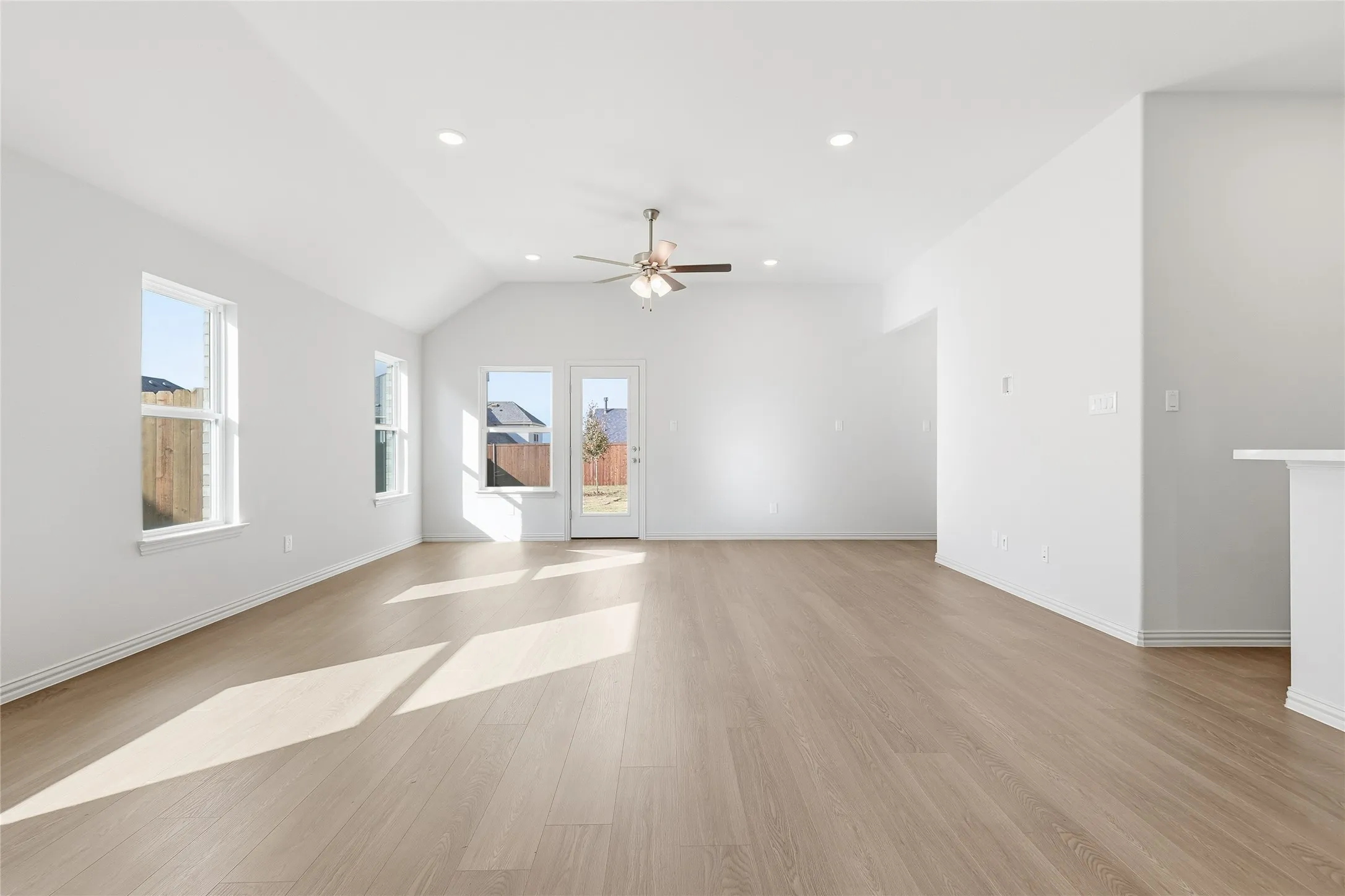 Unfurnished room featuring light wood-style floors, lofted ceiling, ceiling fan, and recessed lighting