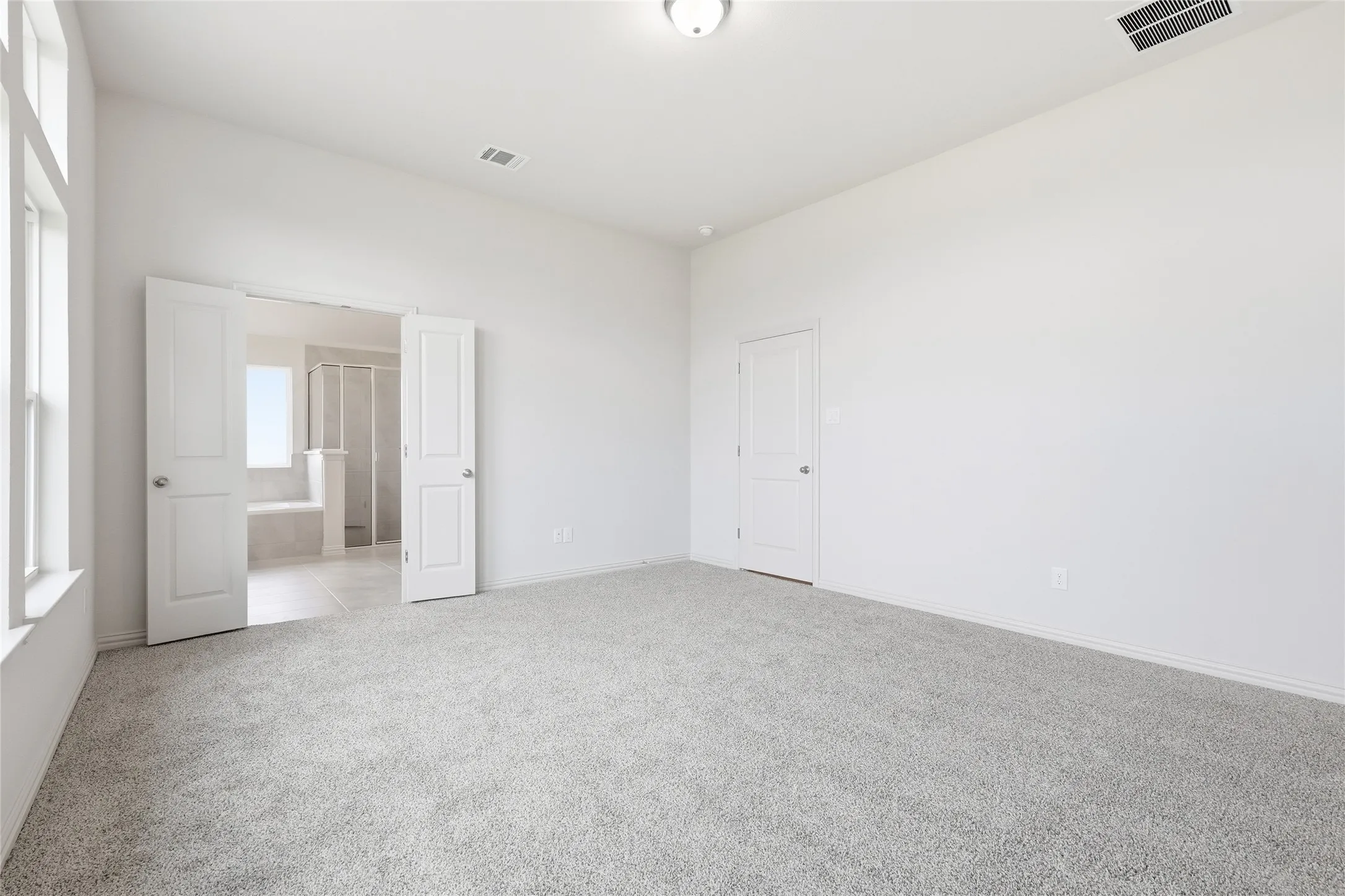 Unfurnished bedroom with light colored carpet and baseboards
