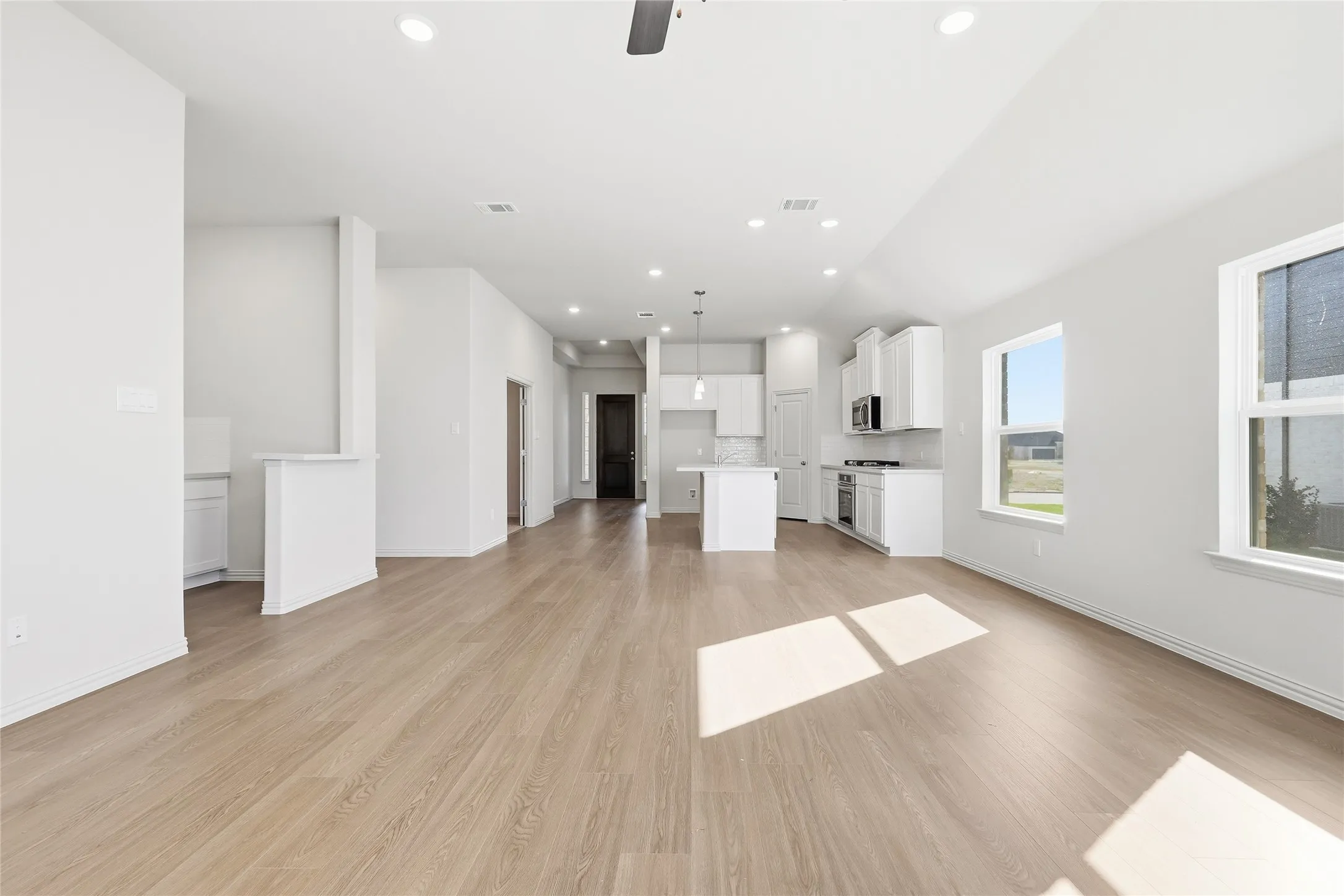 Unfurnished living room with light wood-type flooring, a ceiling fan, and recessed lighting