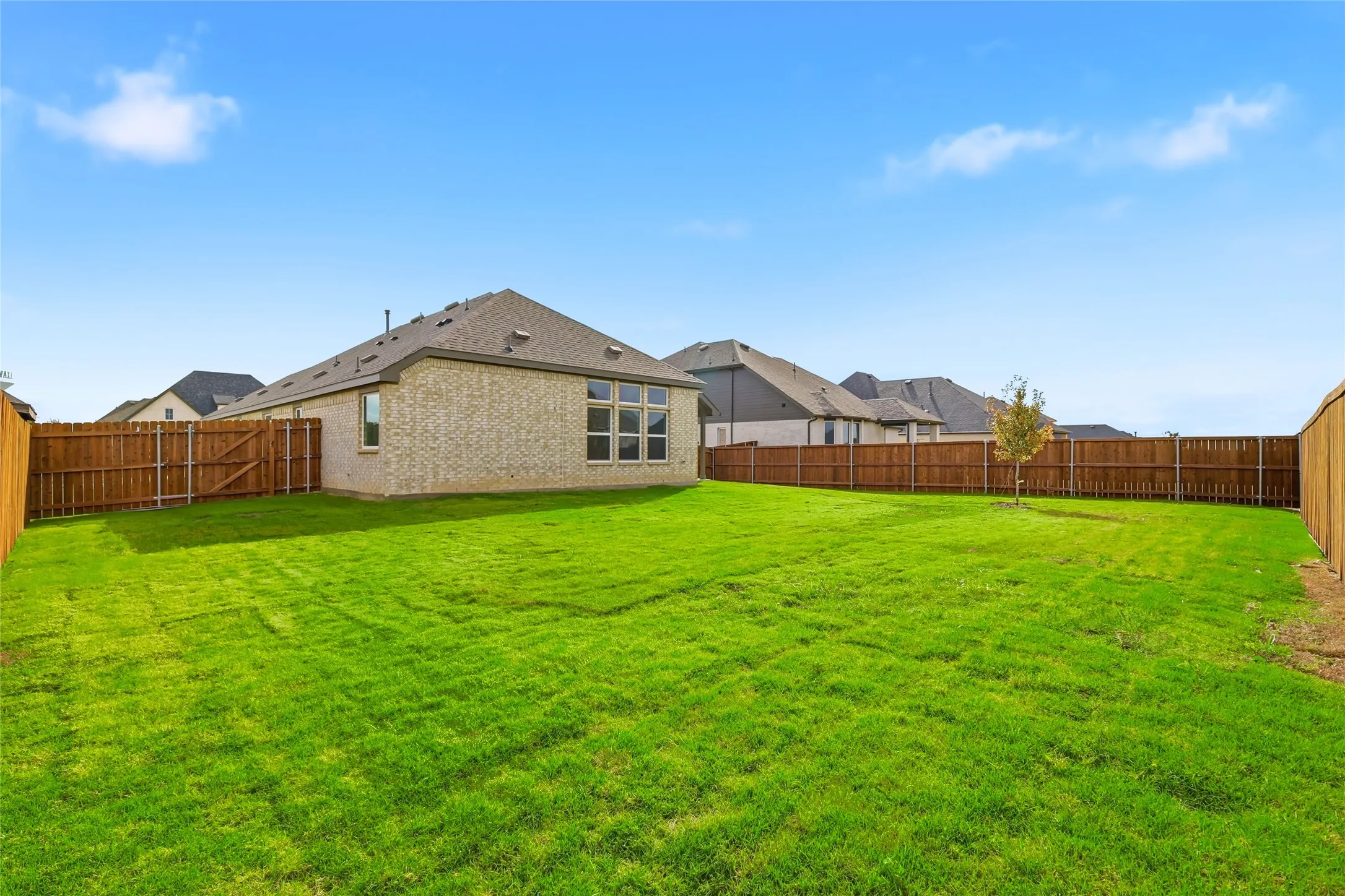 Rear view of property with brick siding and a fenced backyard