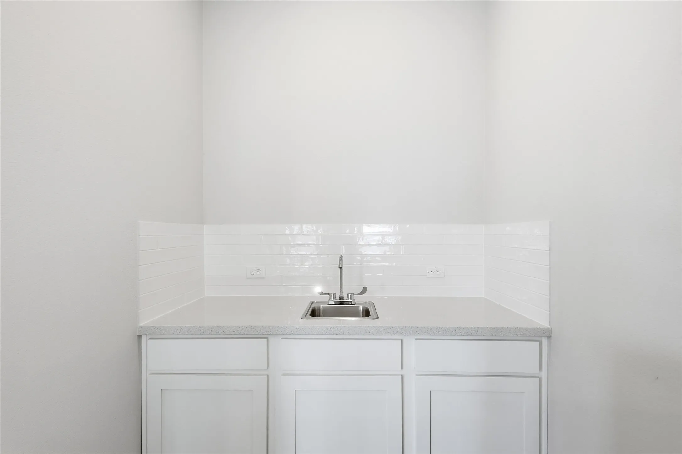 Bar featuring white cabinets, backsplash, and light stone counters