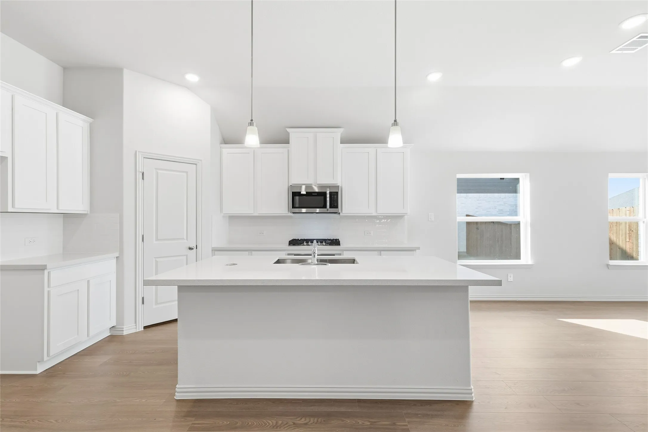 Kitchen featuring white cabinets, tasteful backsplash, a center island with sink, and recessed lighting