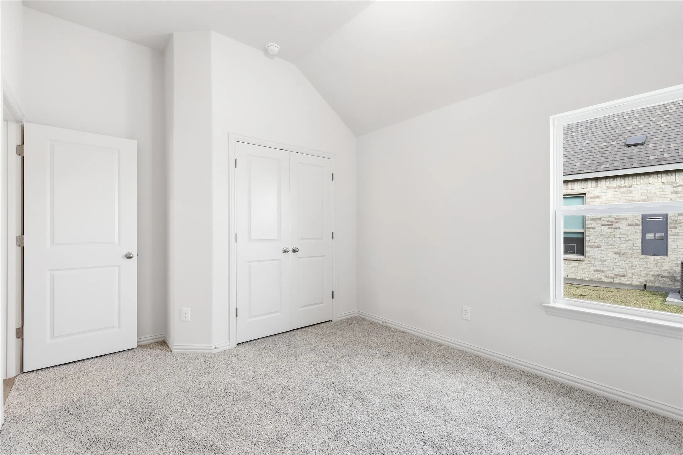Unfurnished bedroom with light carpet, vaulted ceiling, and a closet