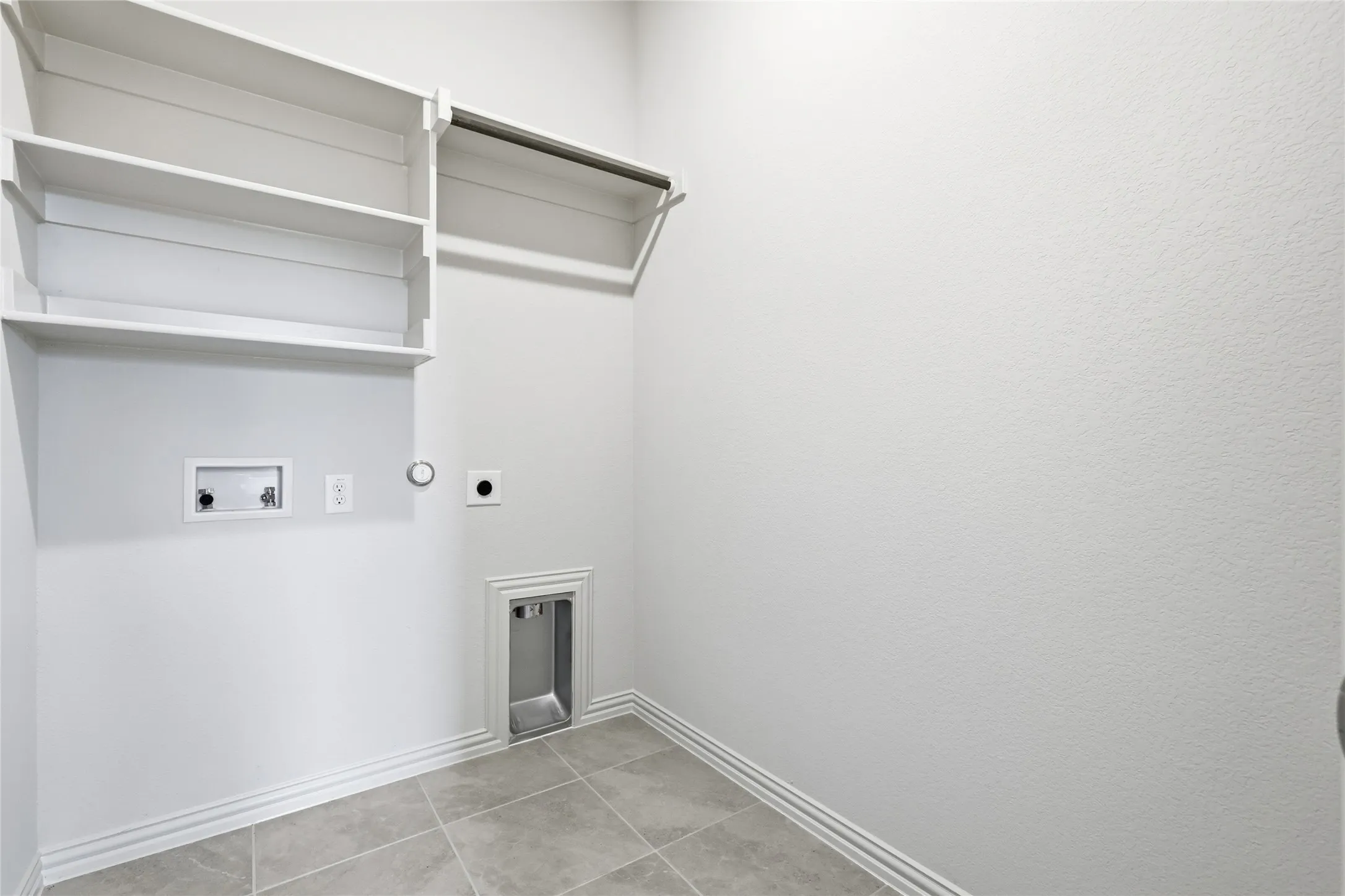Washroom with hookup for a gas dryer, electric dryer hookup, washer hookup, and light tile patterned floors
