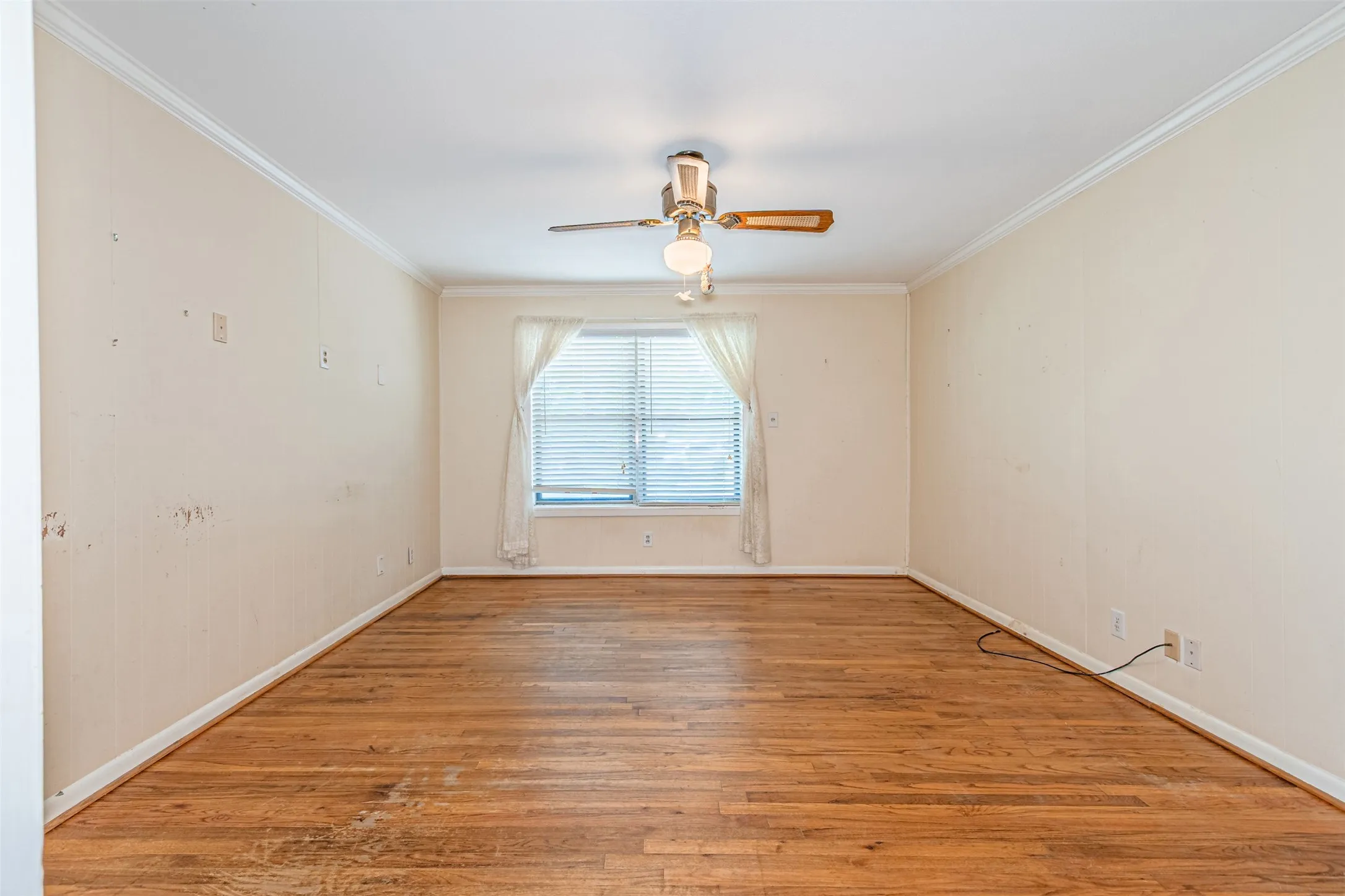 Empty room featuring ornamental molding, light wood finished floors, and a ceiling fan