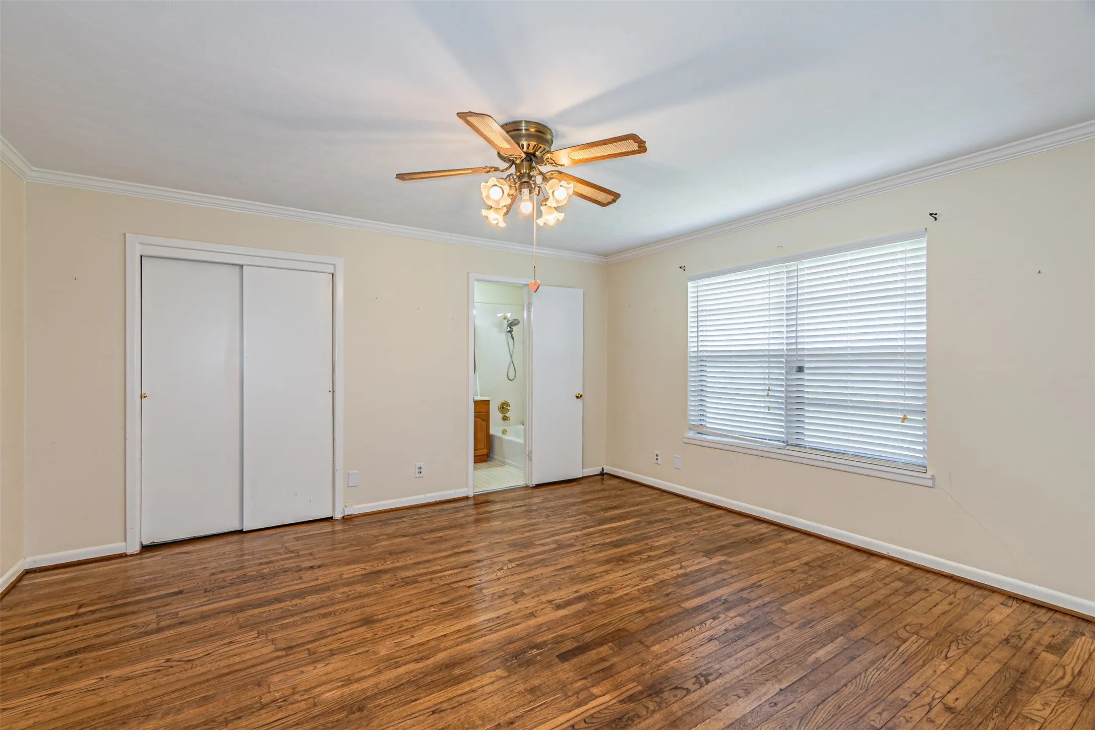 Unfurnished bedroom with wood finished floors, ornamental molding, ensuite bath, a ceiling fan, and a closet