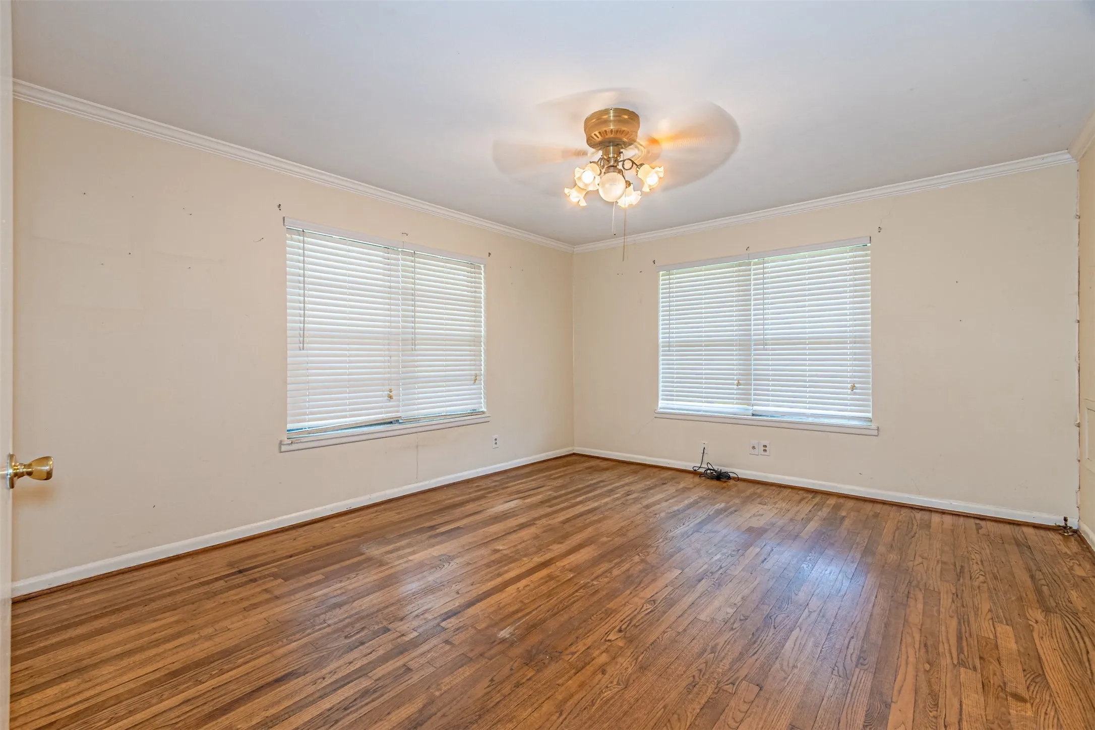 Unfurnished room featuring ornamental molding, healthy amount of natural light, wood-type flooring, and a ceiling fan
