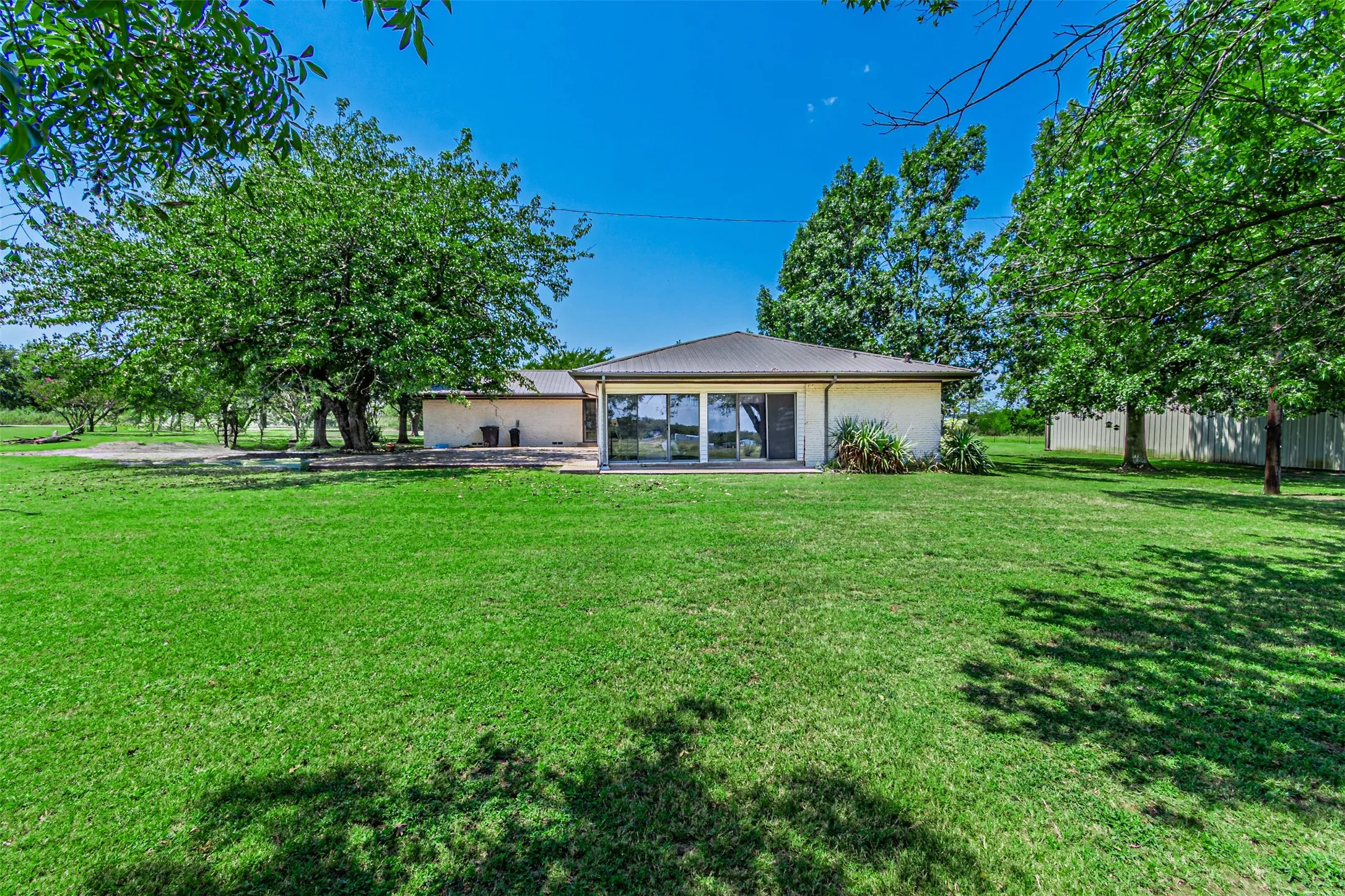 Back of property featuring brick siding and a metal roof