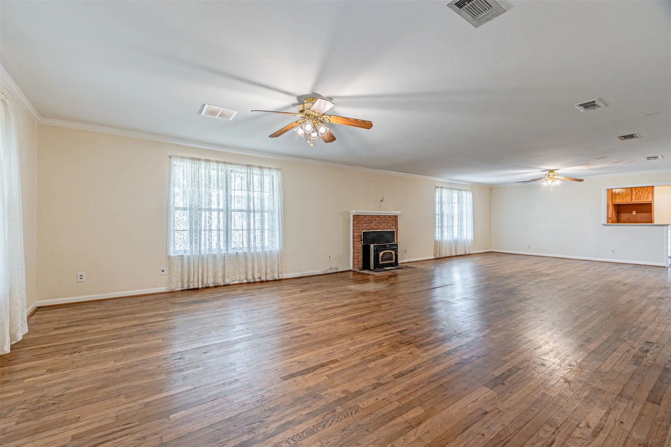 Unfurnished living room featuring hardwood / wood-style flooring, ceiling fan, and crown molding