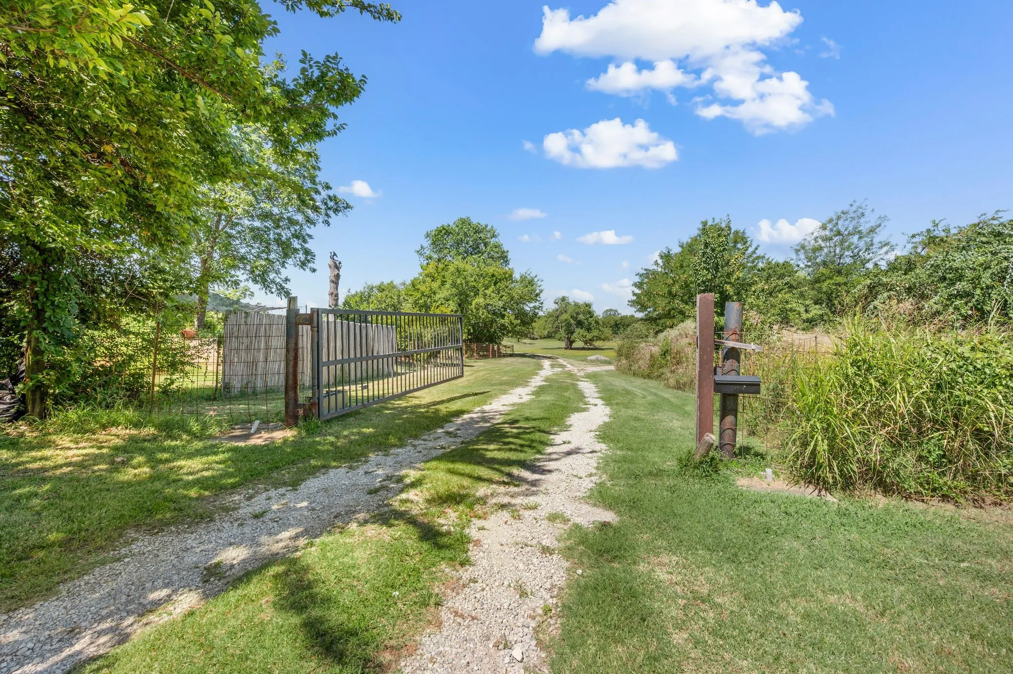 View of dirt / gravel road with a gate and a gated entry