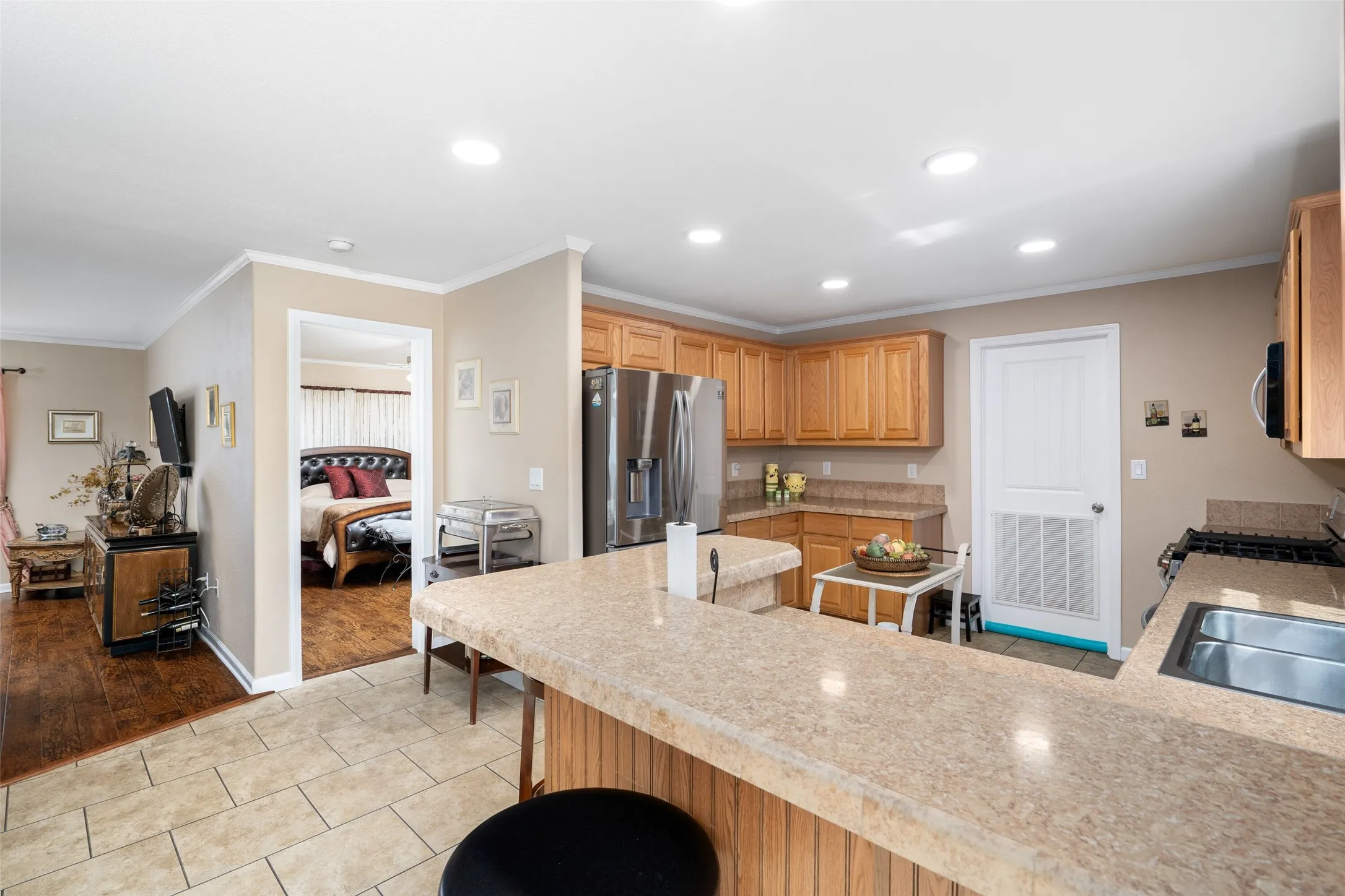 Kitchen with crown molding, light tile patterned flooring, recessed lighting, a kitchen bar, and appliances with stainless steel finishes