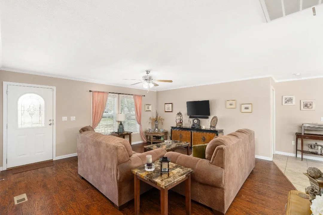 Living room with crown molding, wood finished floors, and a ceiling fan