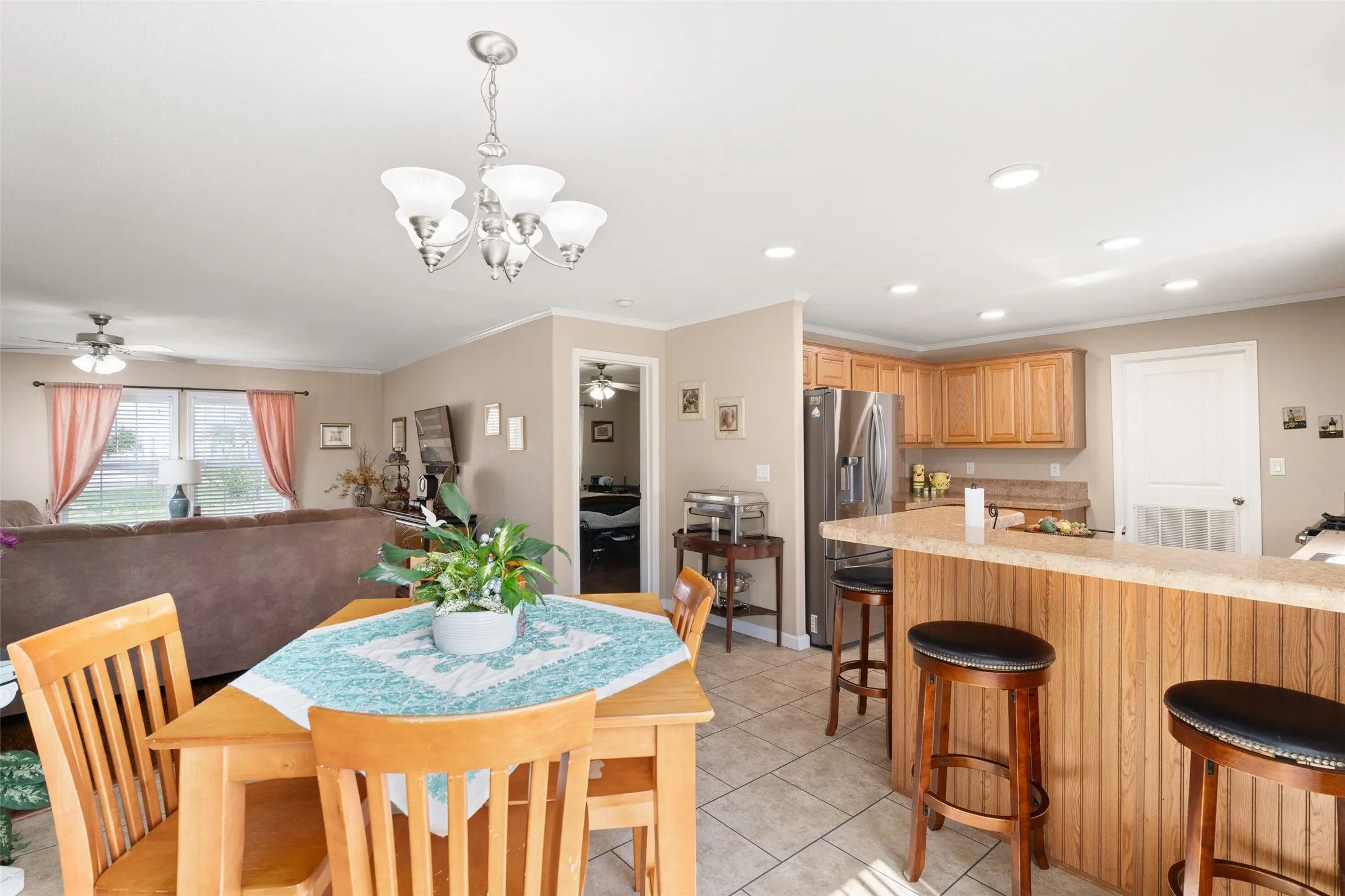 Dining space featuring ceiling fan, crown molding, light tile patterned floors, a chandelier, and recessed lighting