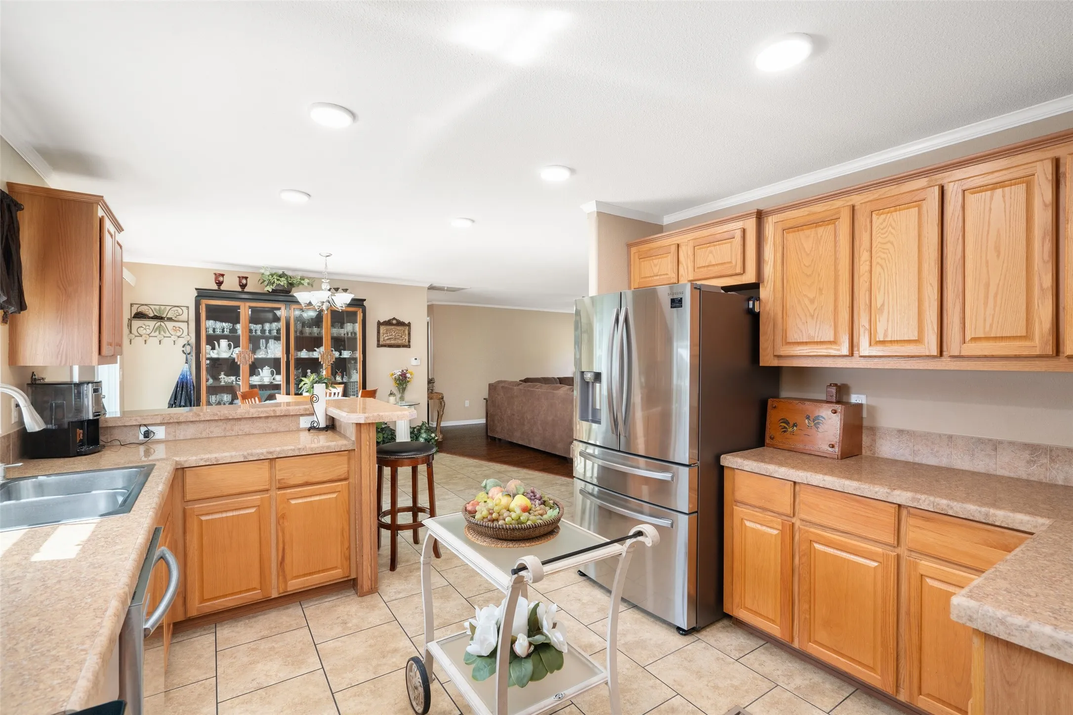 Kitchen with crown molding, a peninsula, stainless steel appliances, a chandelier, and open floor plan