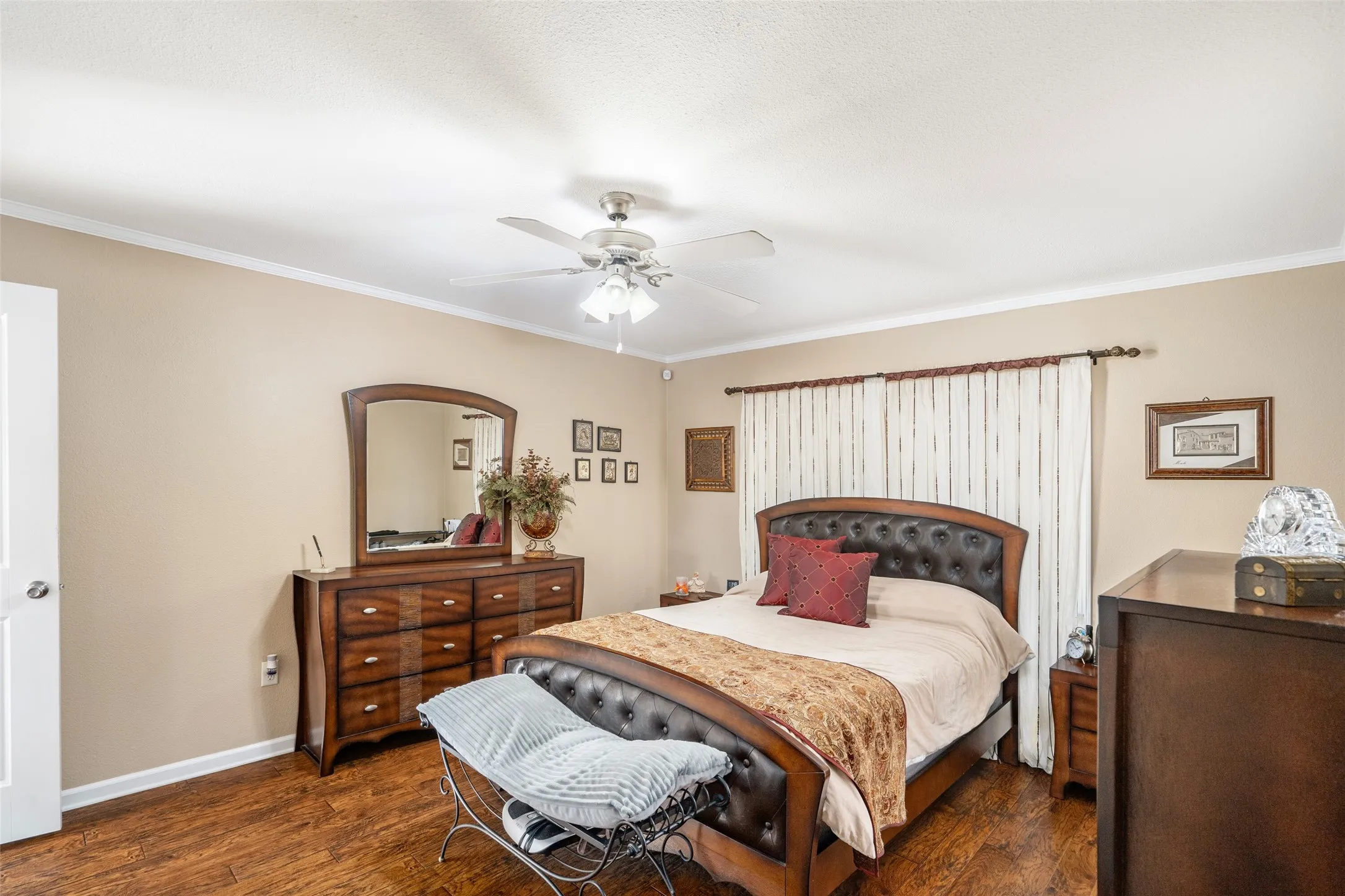 Bedroom featuring dark wood-style flooring, crown molding, and a ceiling fan