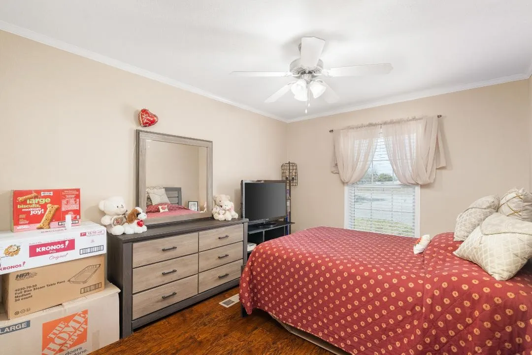 Bedroom featuring ornamental molding, dark wood finished floors, and ceiling fan