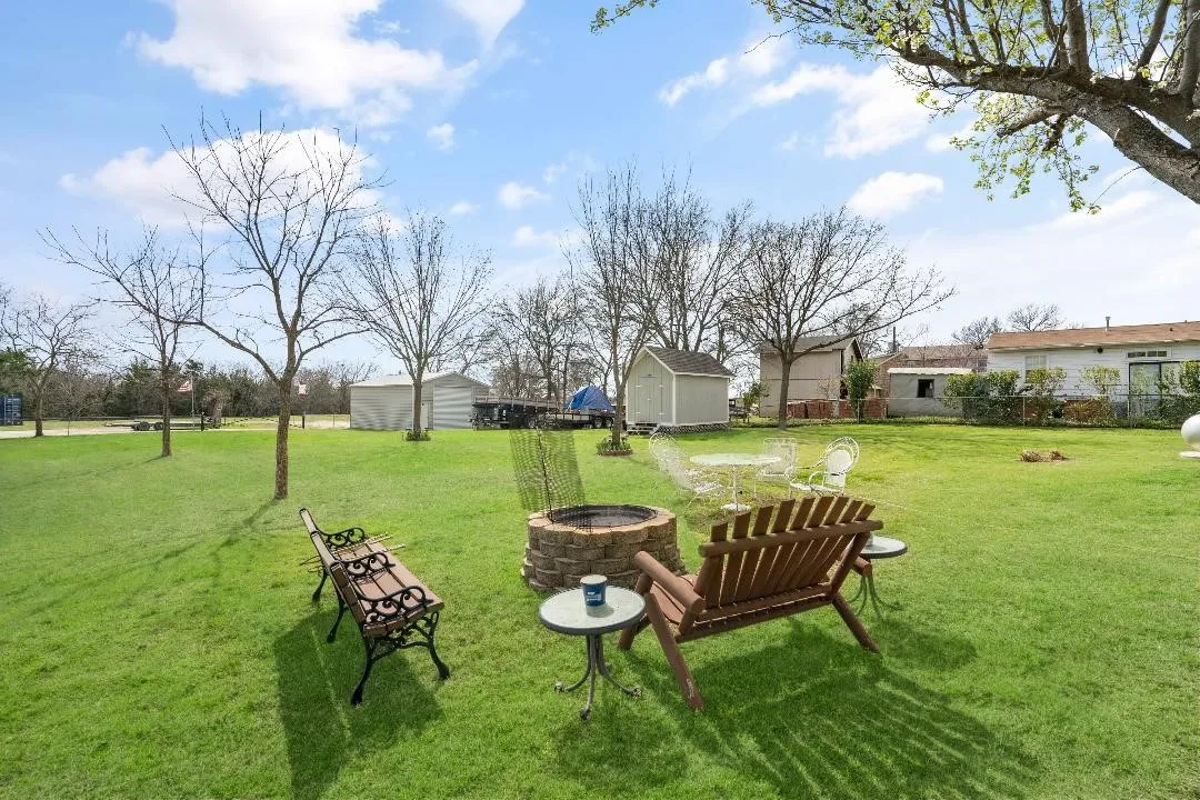 View of grassy yard featuring a storage unit and a fire pit