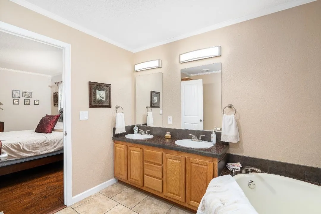 Ensuite bathroom with ornamental molding, a garden tub, and light tile patterned floors
