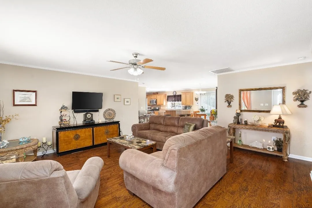 Living room with crown molding, dark wood-style floors, and ceiling fan