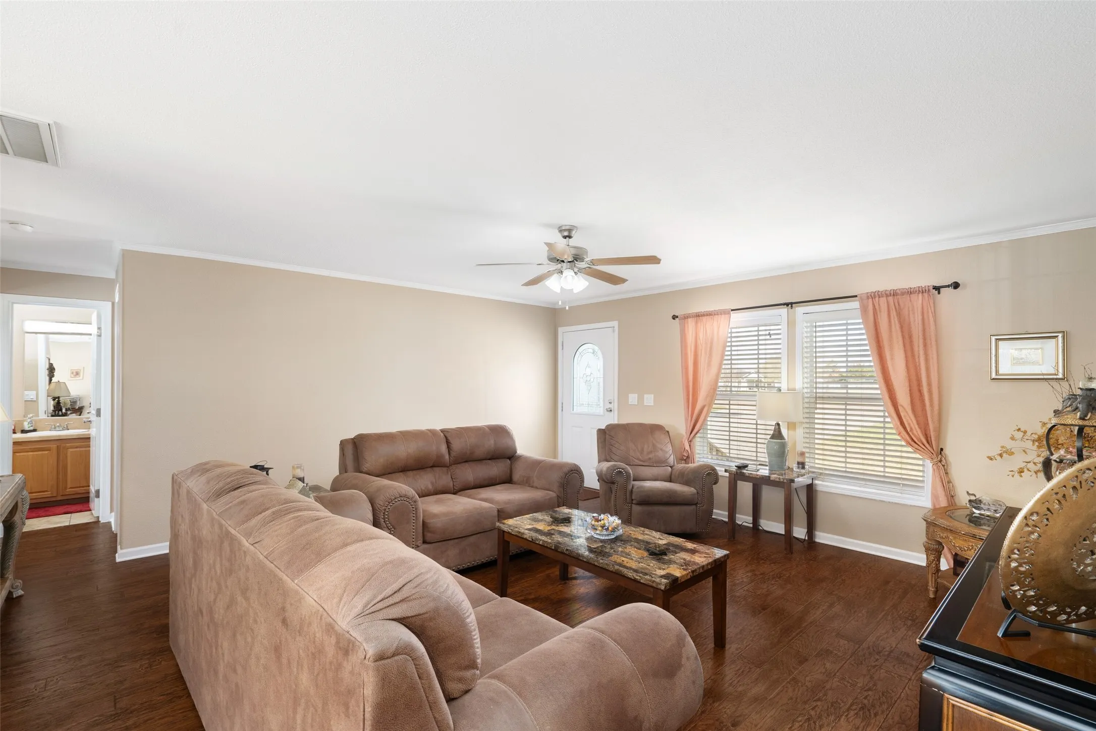 Living room with dark wood-style floors, crown molding, and a ceiling fan