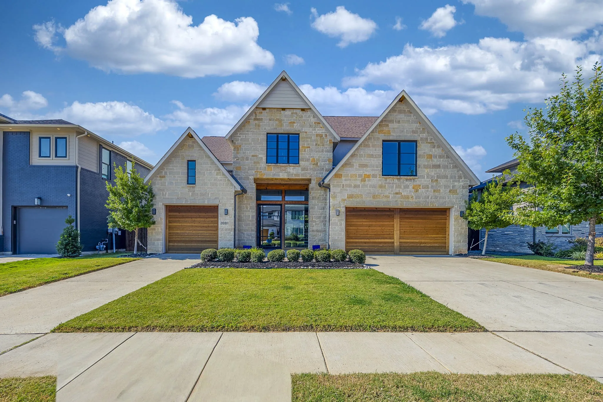View of front of house featuring a garage, stone siding, and driveway