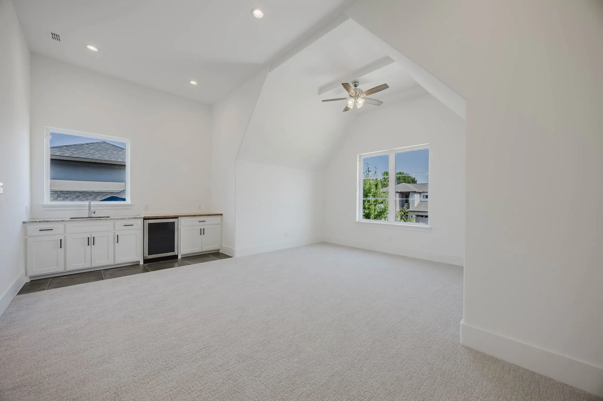 Unfurnished living room with light colored carpet, vaulted ceiling, recessed lighting, a ceiling fan, and beverage cooler