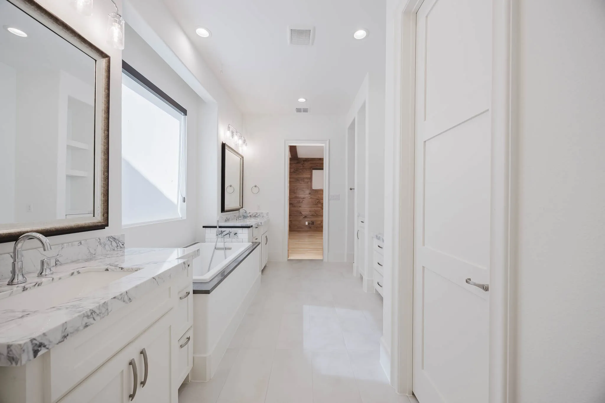 Bathroom featuring two vanities, a garden tub, recessed lighting, and light tile patterned floors