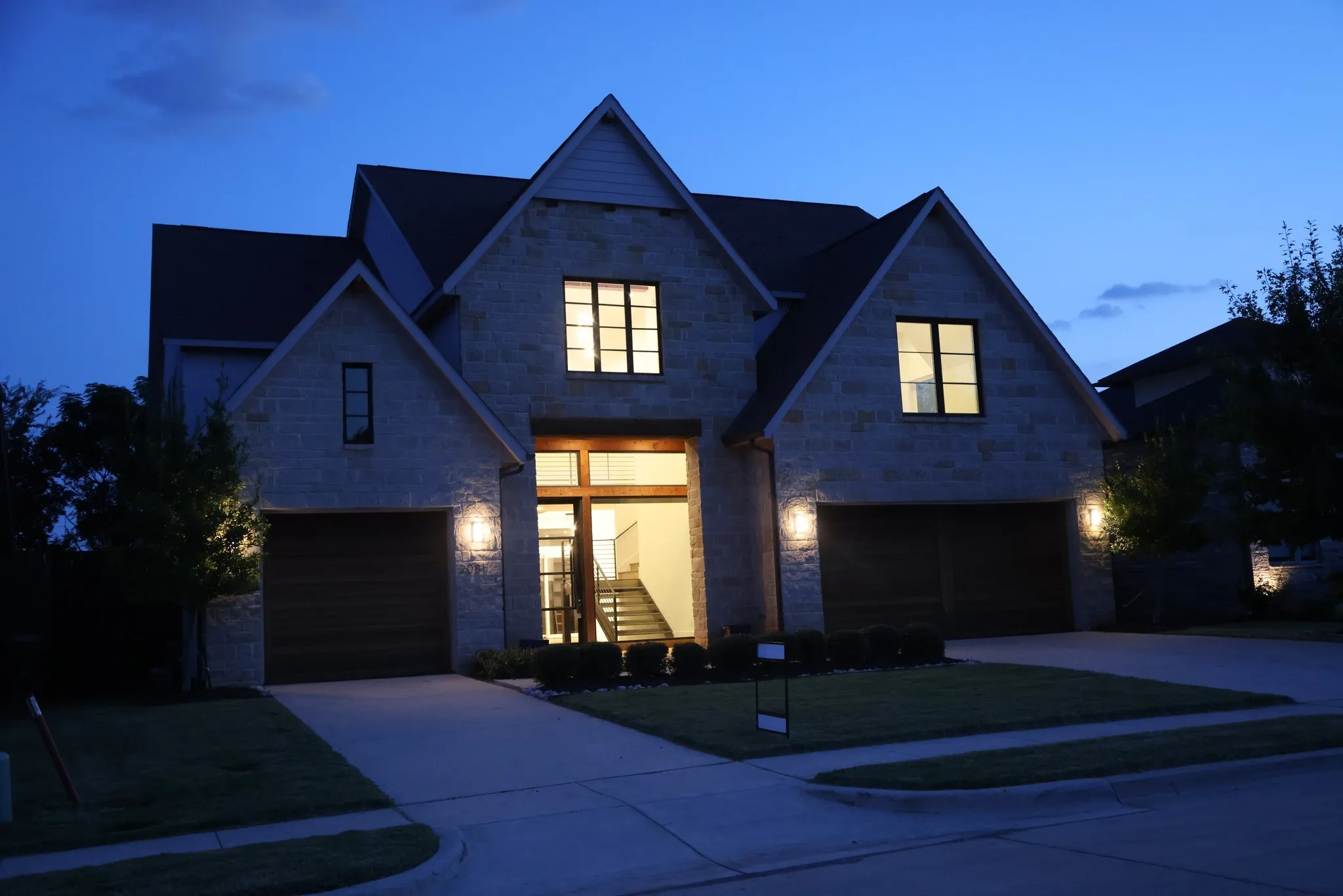 View of front of house featuring a garage, concrete driveway, and stone siding